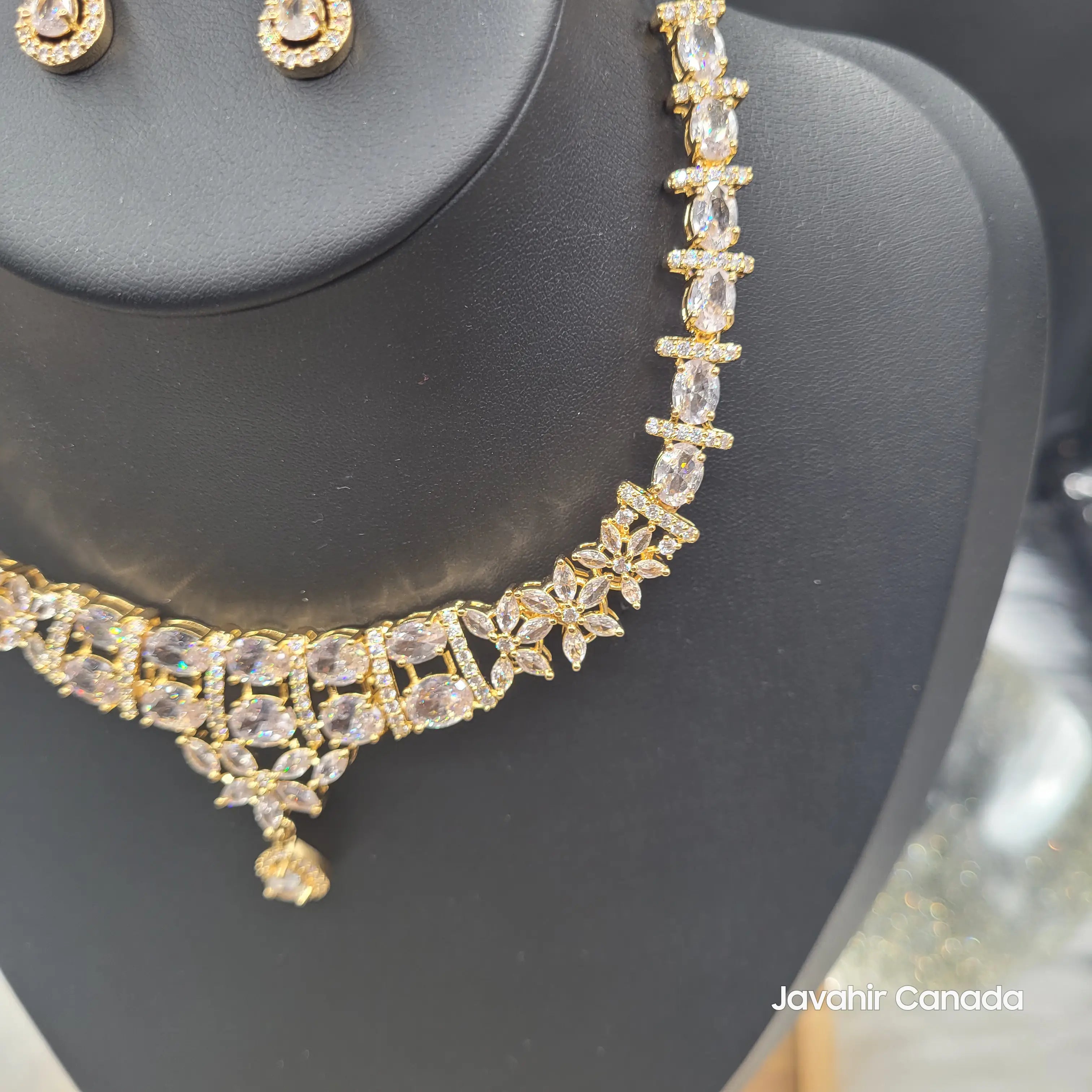 Display of JV150 gold variant with clear CZ stones and matching earrings on bust stand.