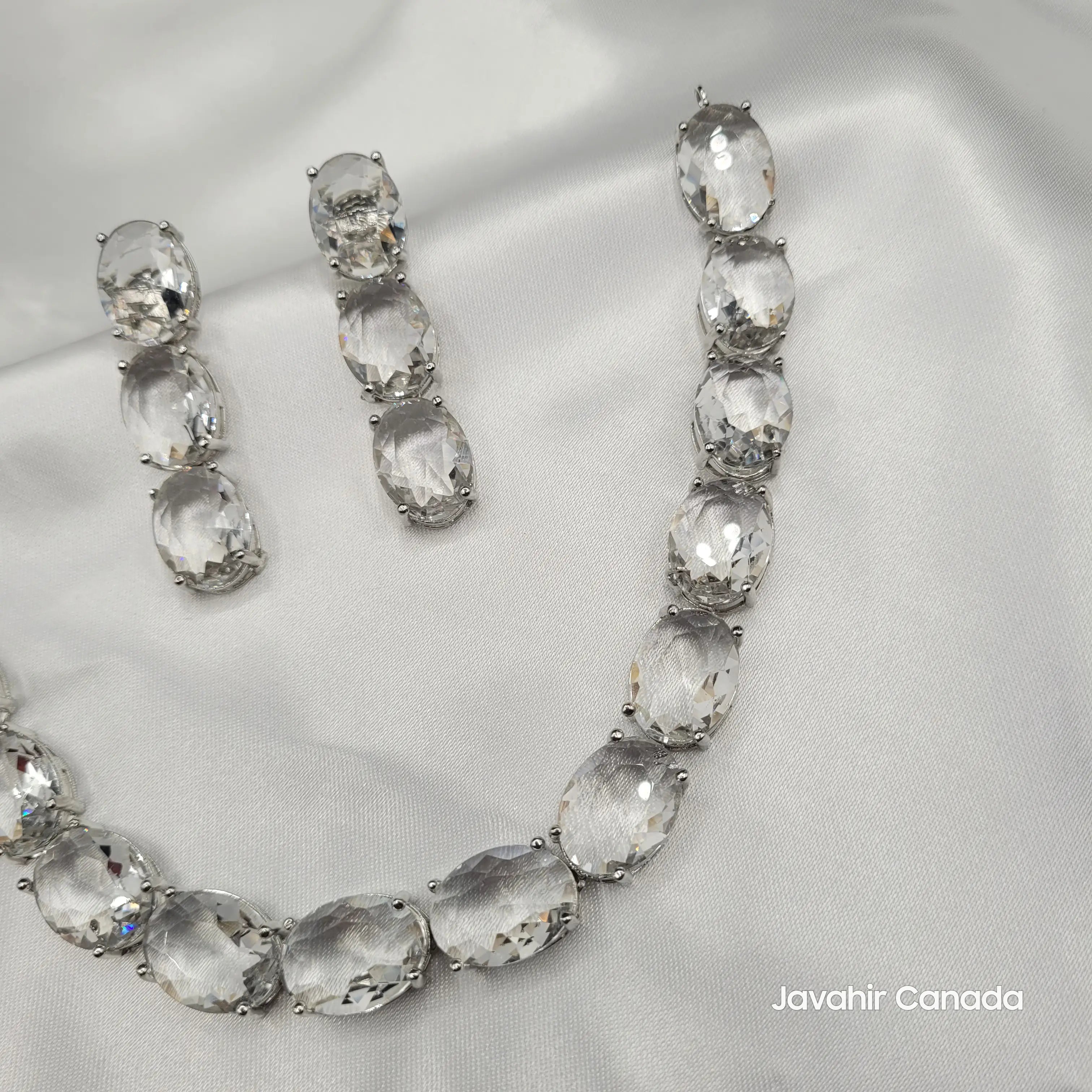 Close-up of clear CZ oval-cut earrings from JV151 set on satin background