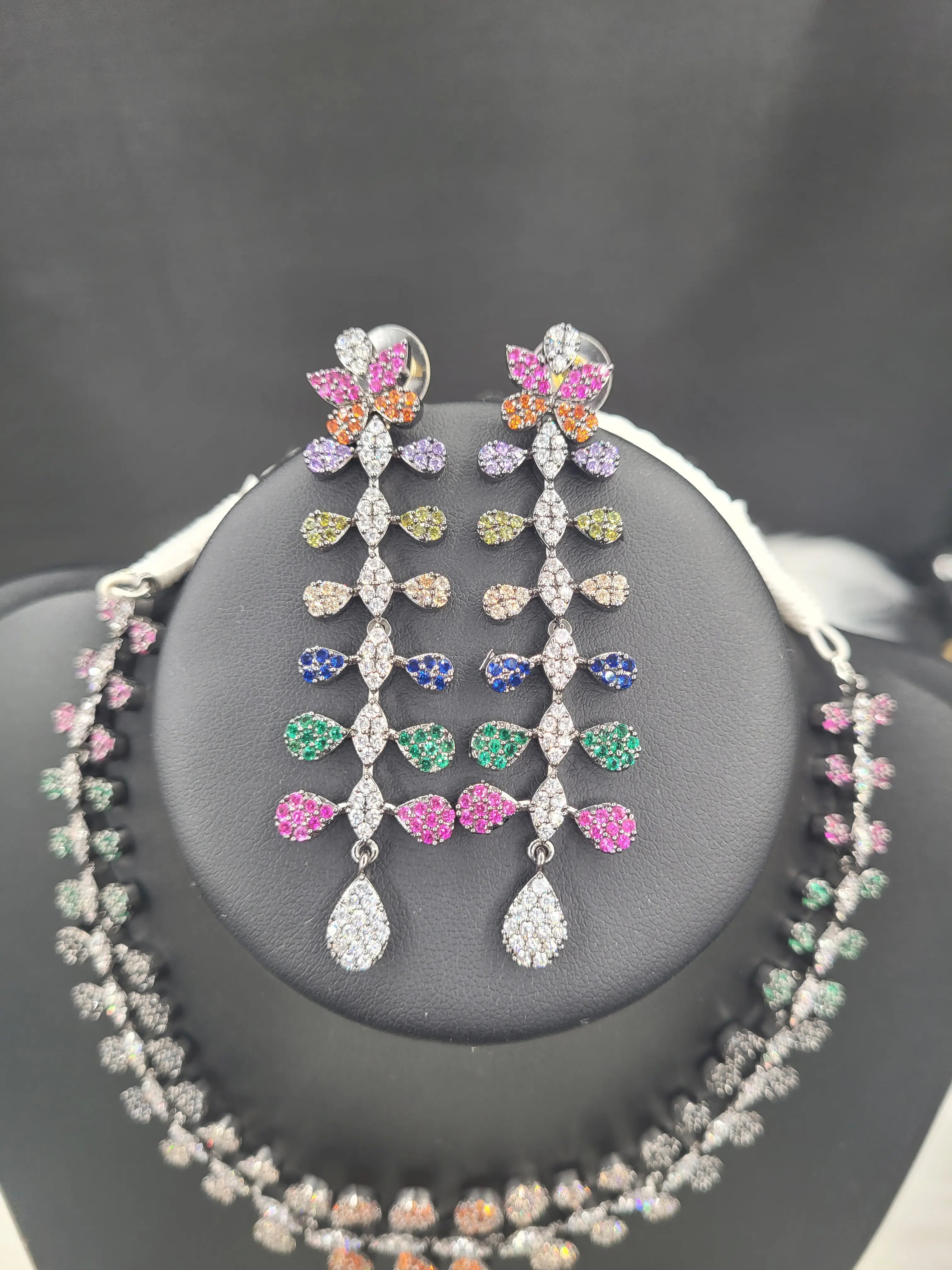 Close-up of long multicolour CZ earrings from JV152 set with teardrop and floral motifs in orange, pink, purple, green, and blue stones.