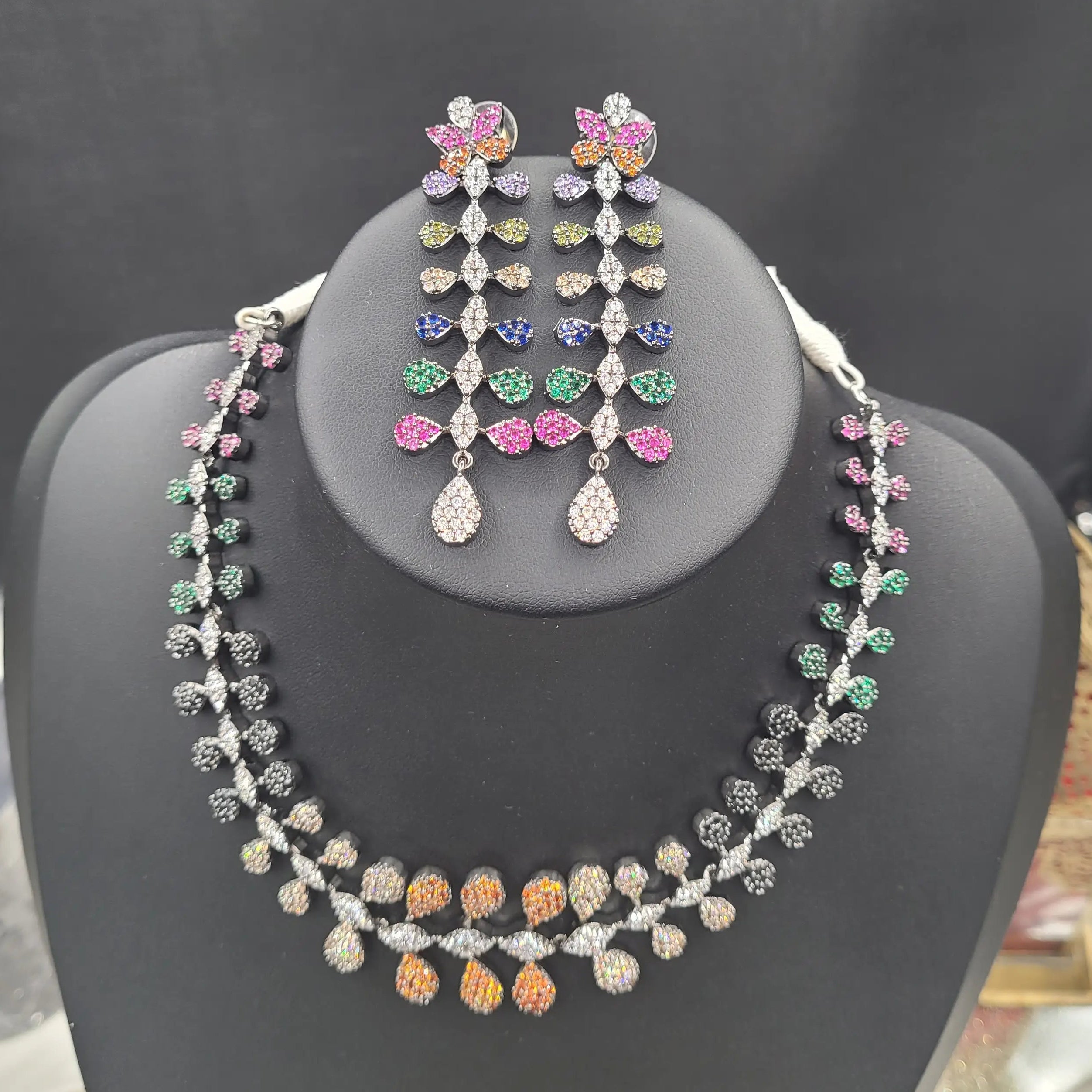 Full view of JV152 multicolour zircon necklace set with matching floral drop earrings displayed on black stand.