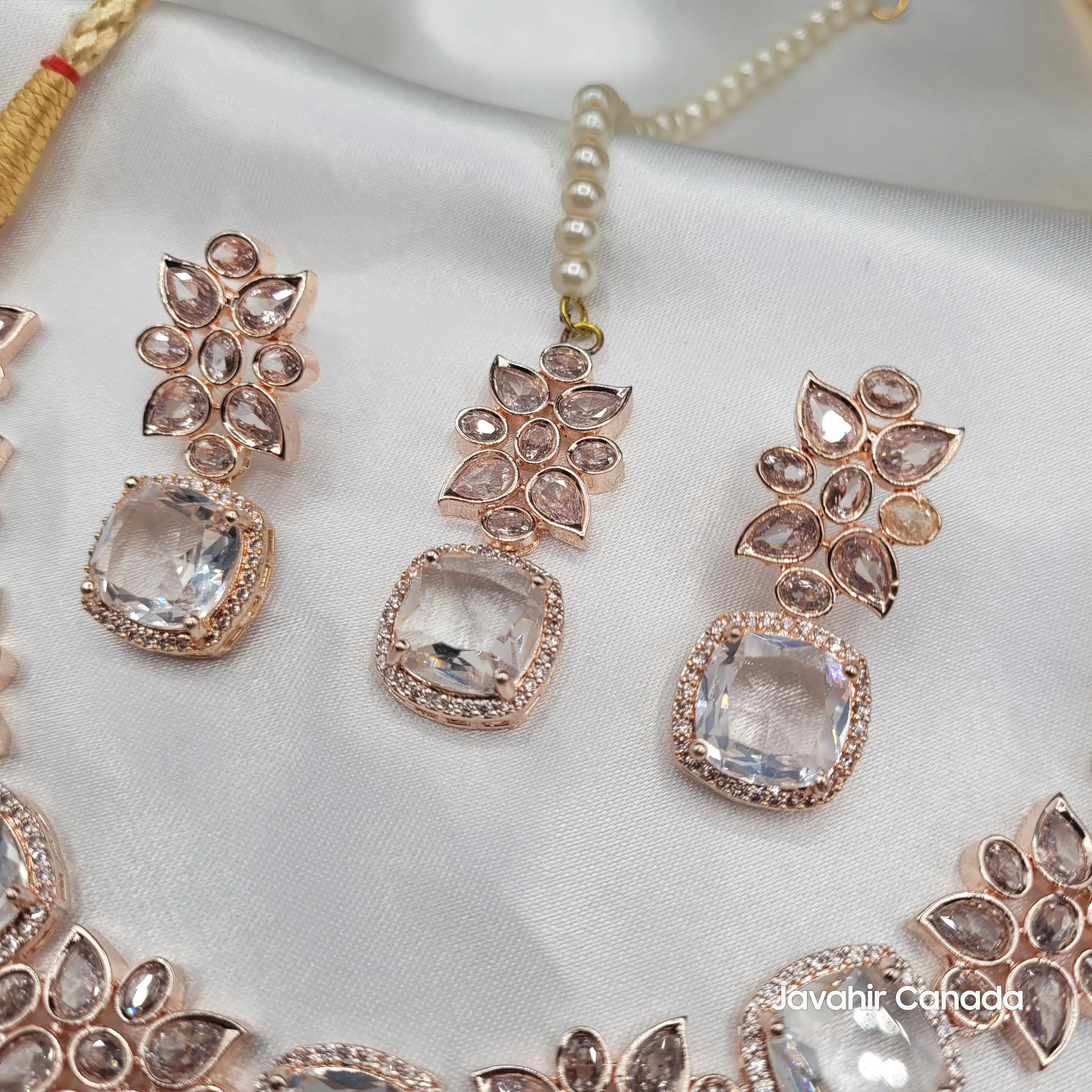 Close-up of rose gold plated earrings and tikka with cushion-cut clear zircon stones and floral CZ arrangement, part of the JV153 necklace set.