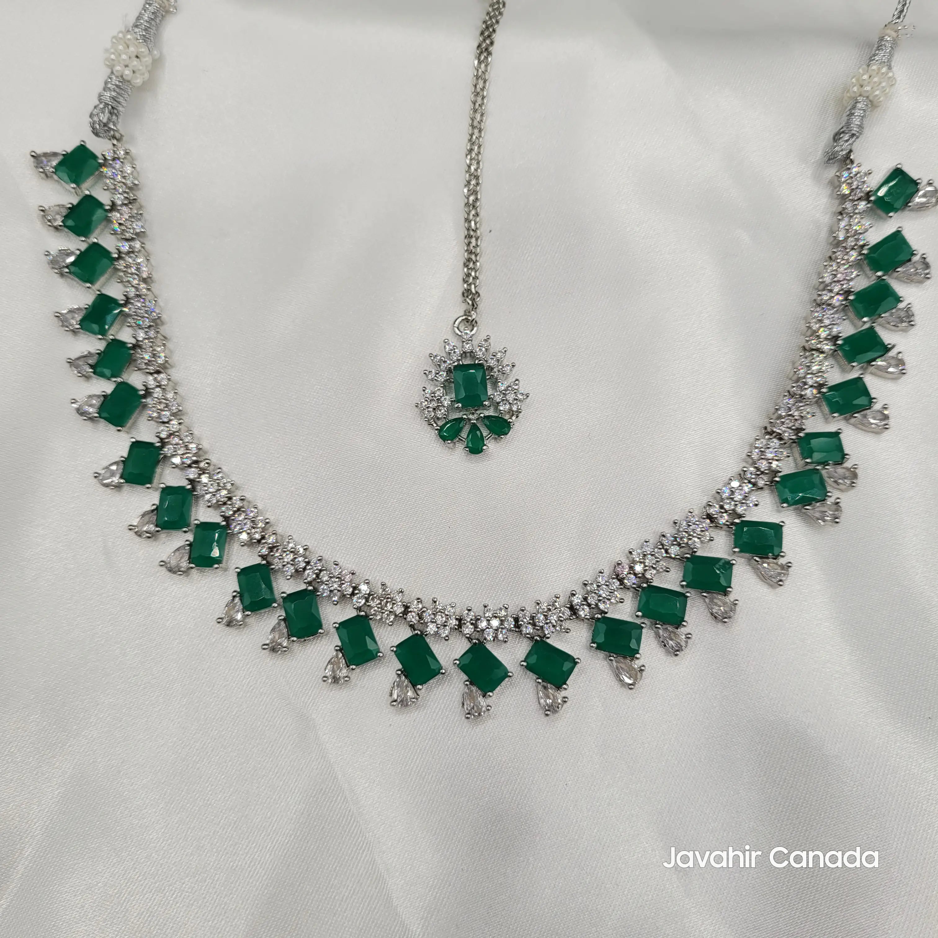 Full JV19 necklace set laid out on white fabric featuring maang tikka and intricate stonework.