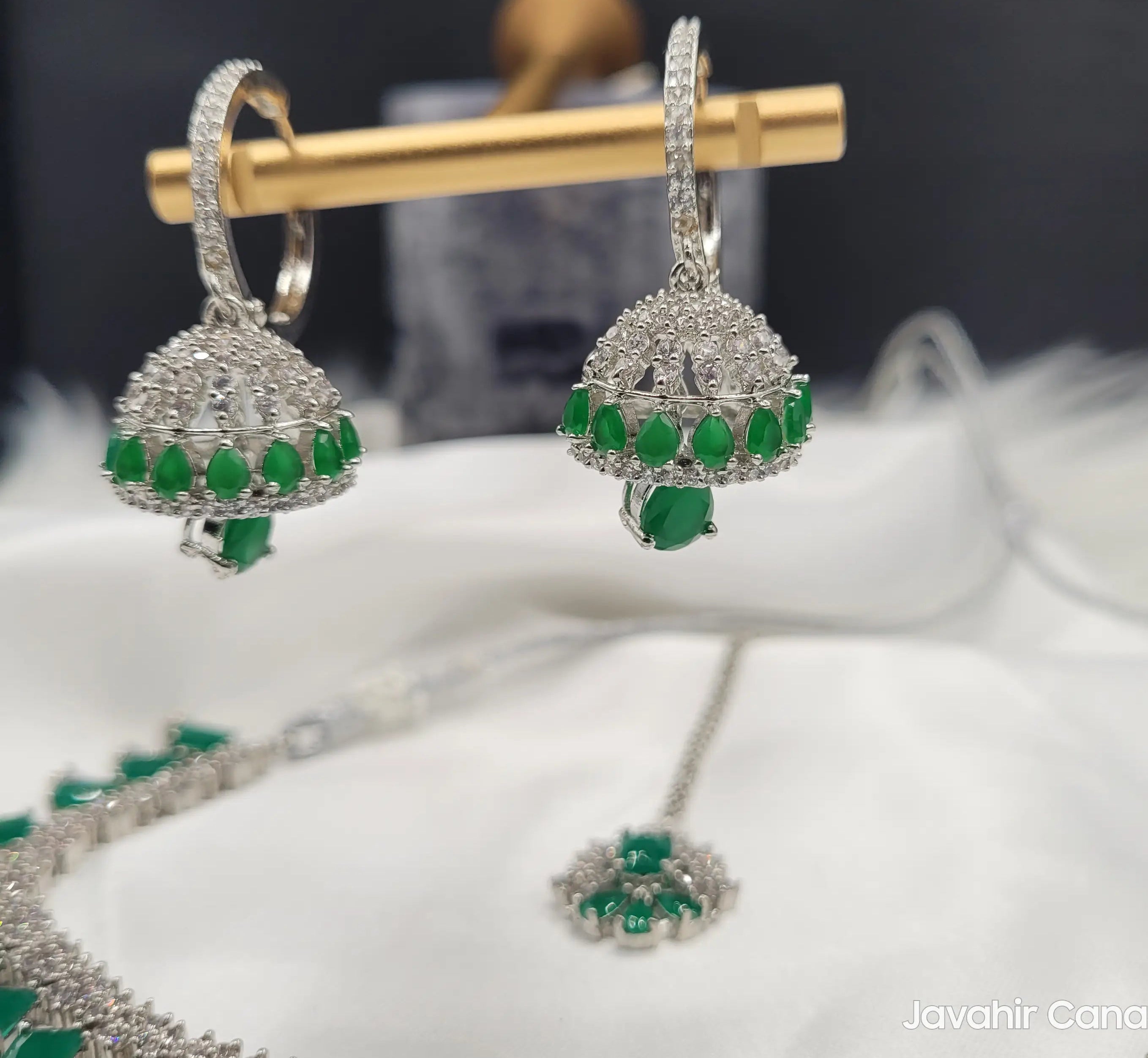 Zoomed-in shot of jhumka earrings from JV19 showing green teardrop stones and pave CZ setting.
