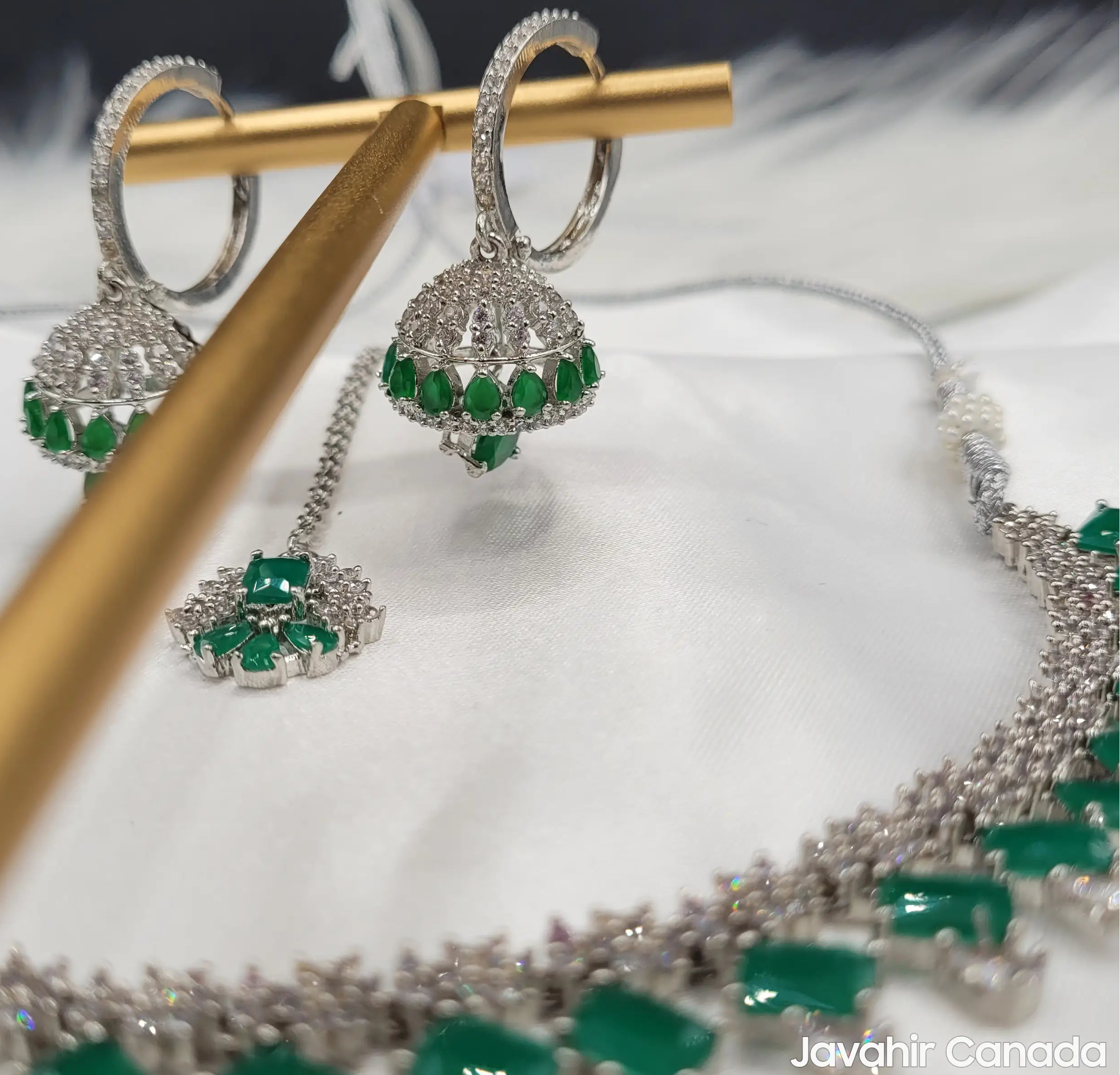 Side view of JV19 earrings hanging on gold rod with necklace and tikka in background for styling inspiration.