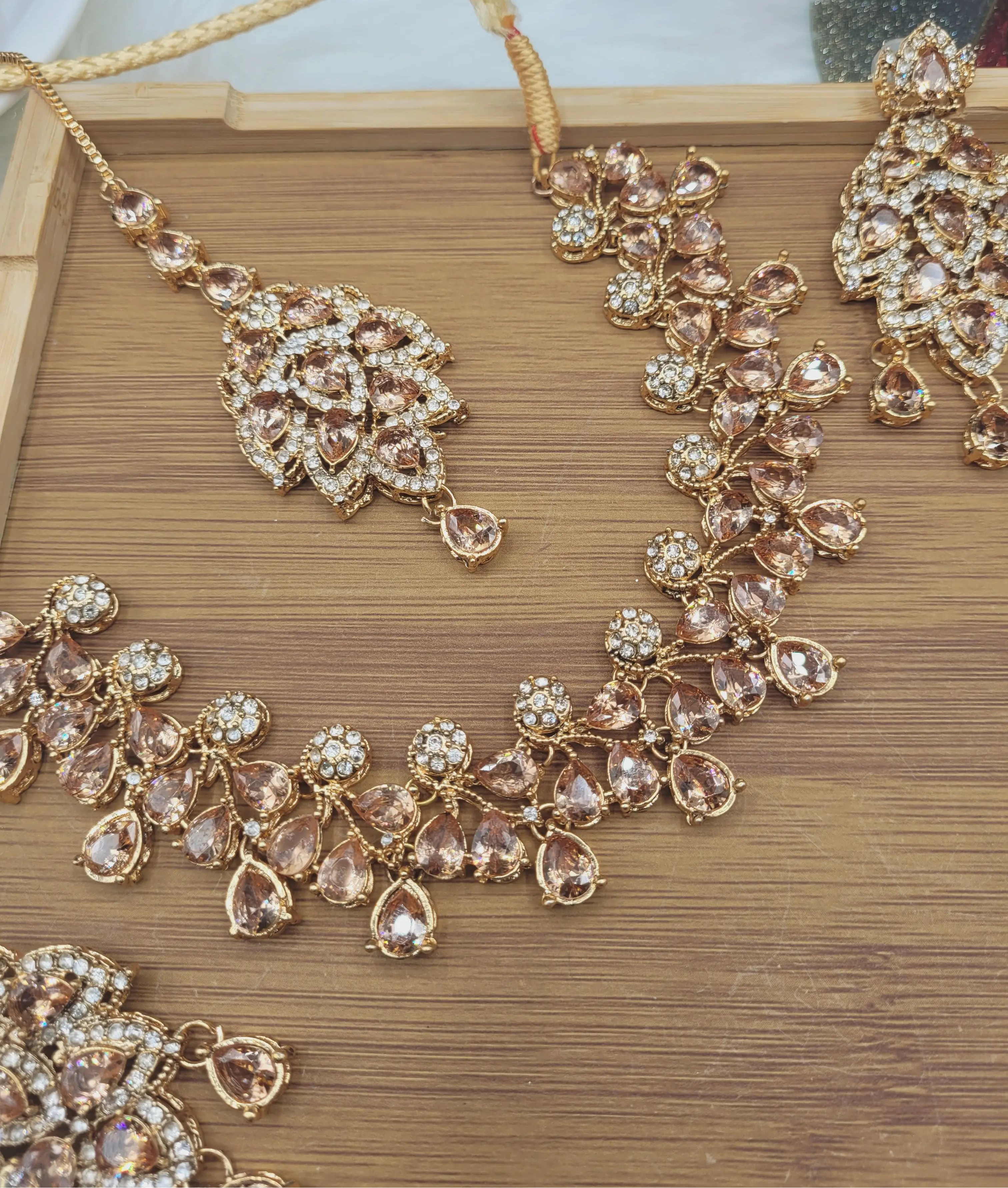 JV20 champagne necklace set arranged flat on wooden tray