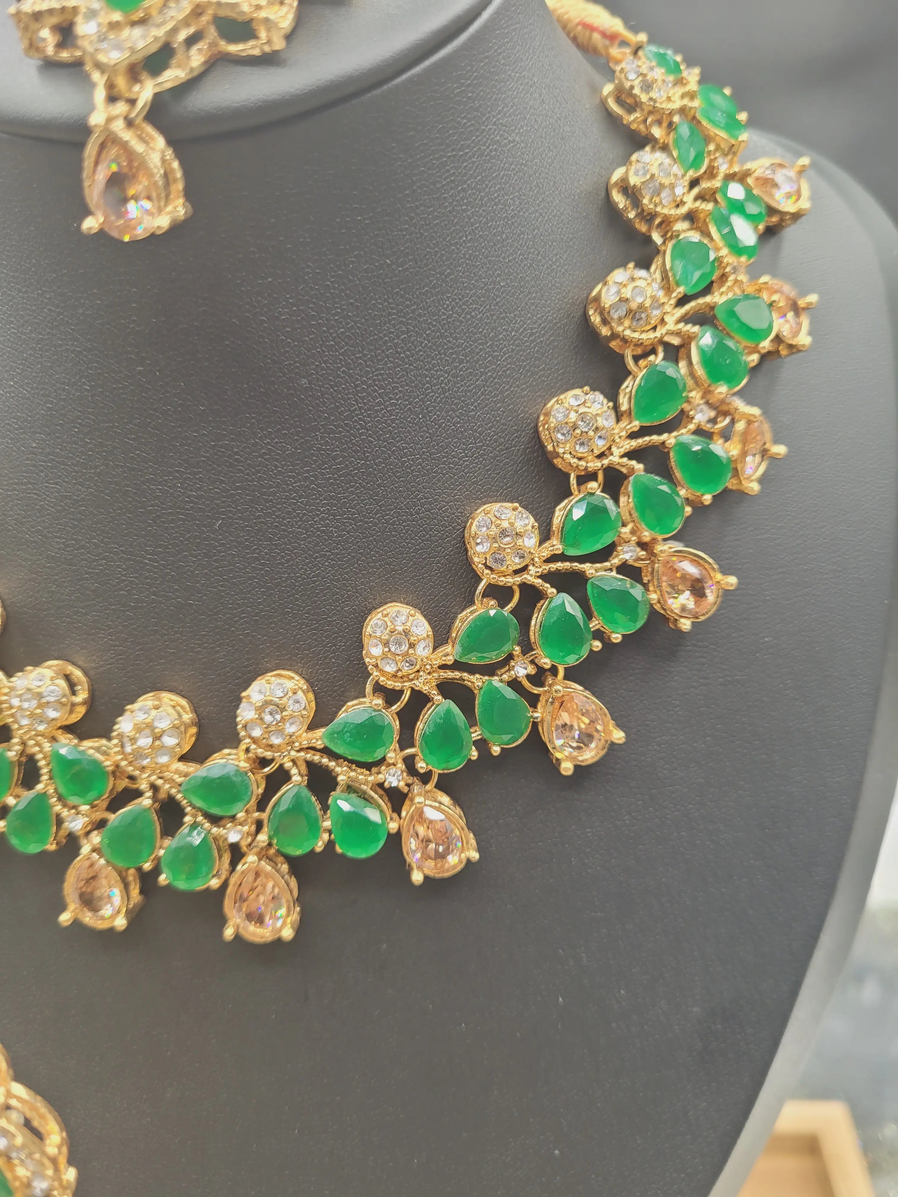 JV20 emerald green necklace close-up, highlighting clustered teardrop green stones and champagne danglers.
