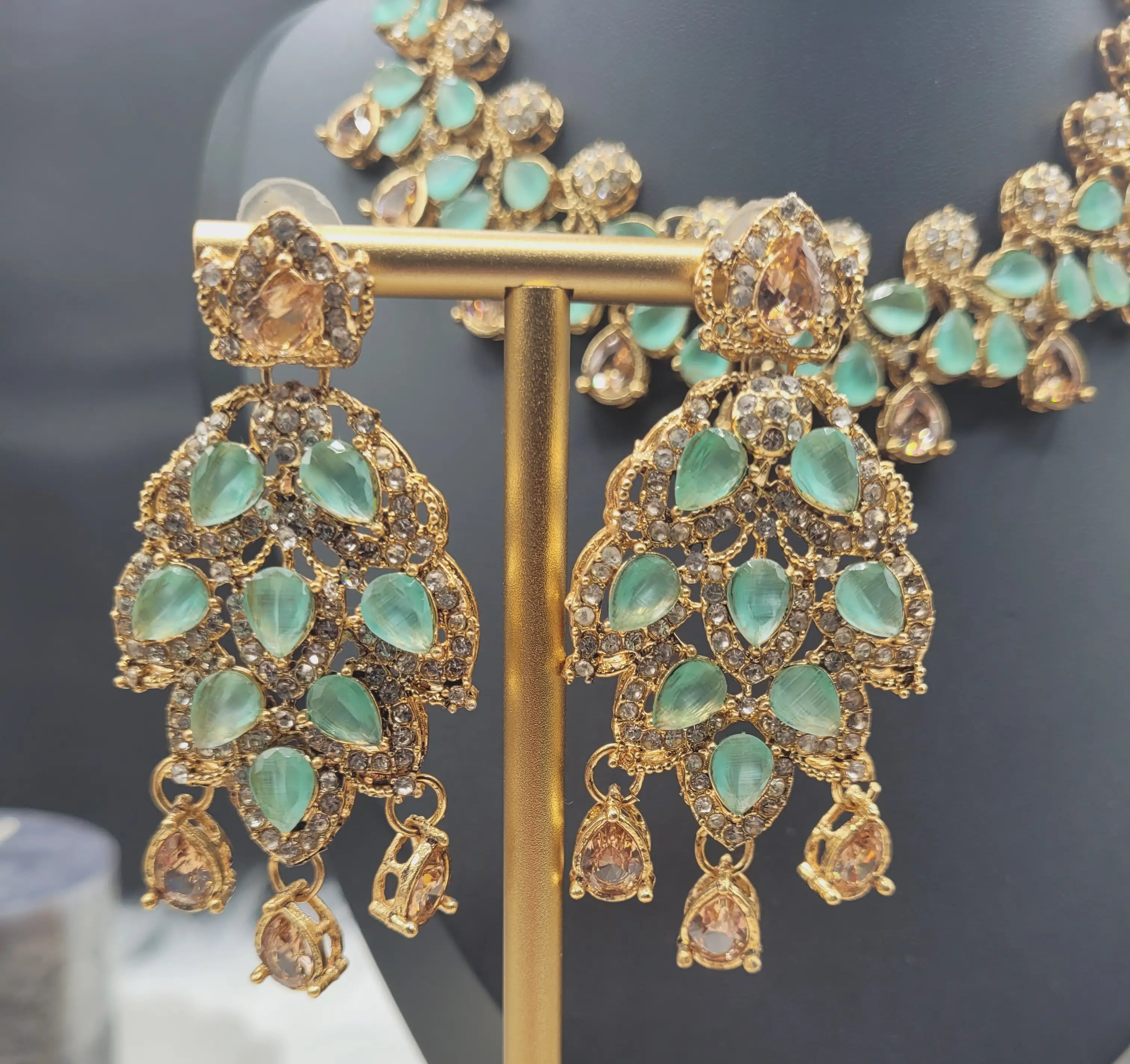 Mint green JV20 earrings on gold stand, featuring teardrop-shaped gemstones and sparkling CZ accents.