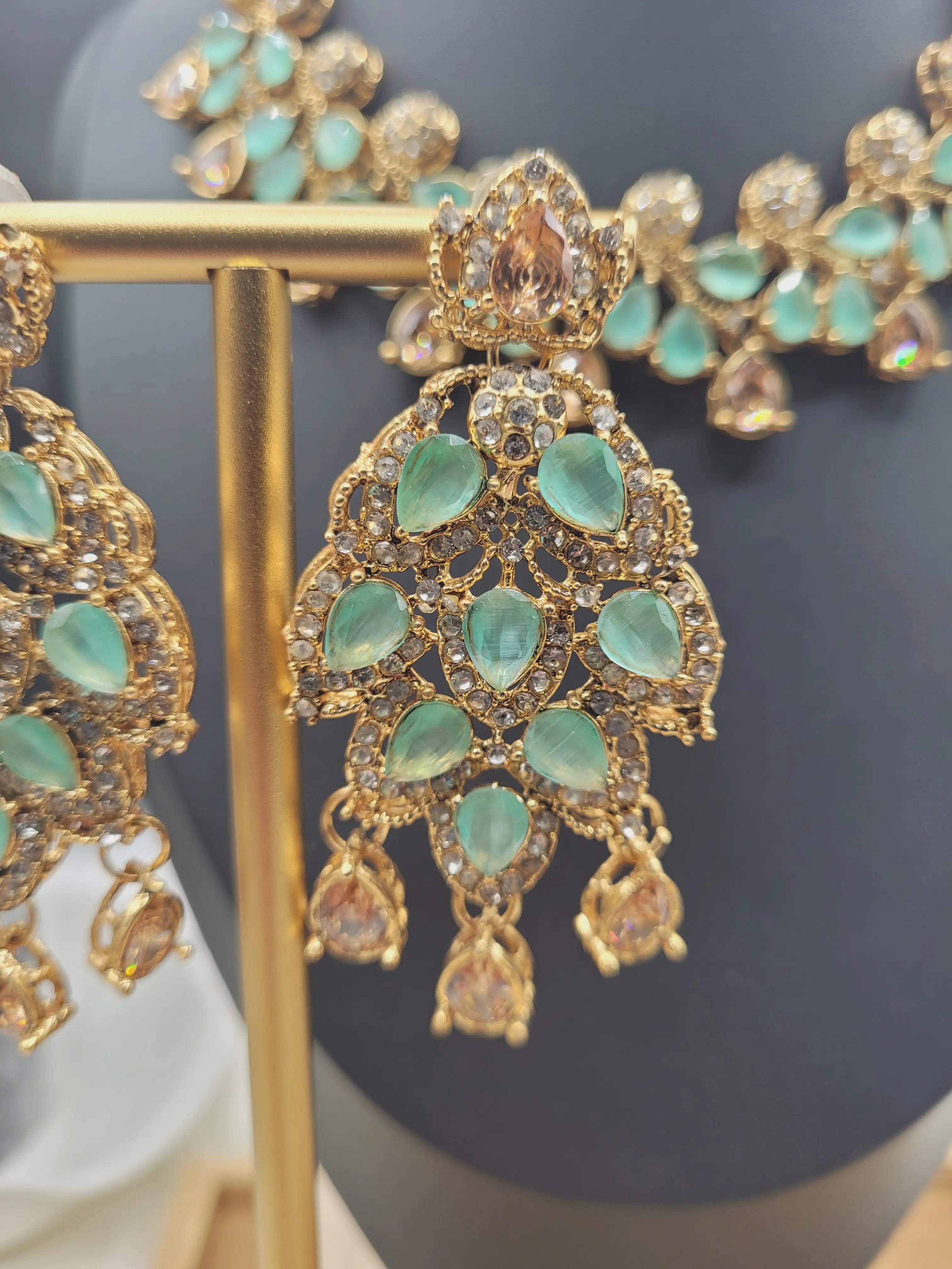 JV20 mint green earrings close-up, featuring layered teardrop gemstones and American diamond accents on gold setting.
