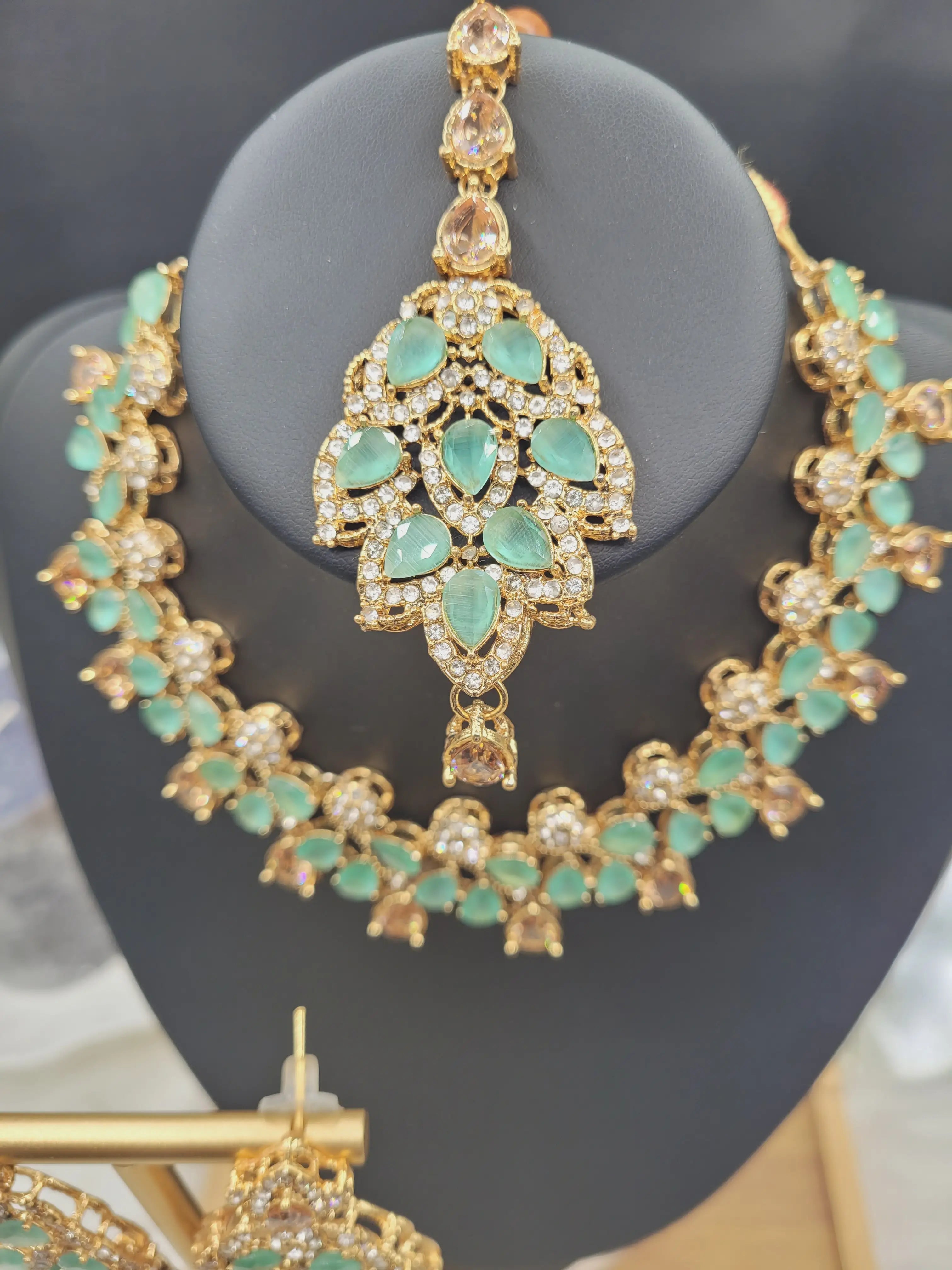 Close-up of JV20 mint green maang tikka with teardrop CZ stones, displayed with matching necklace.