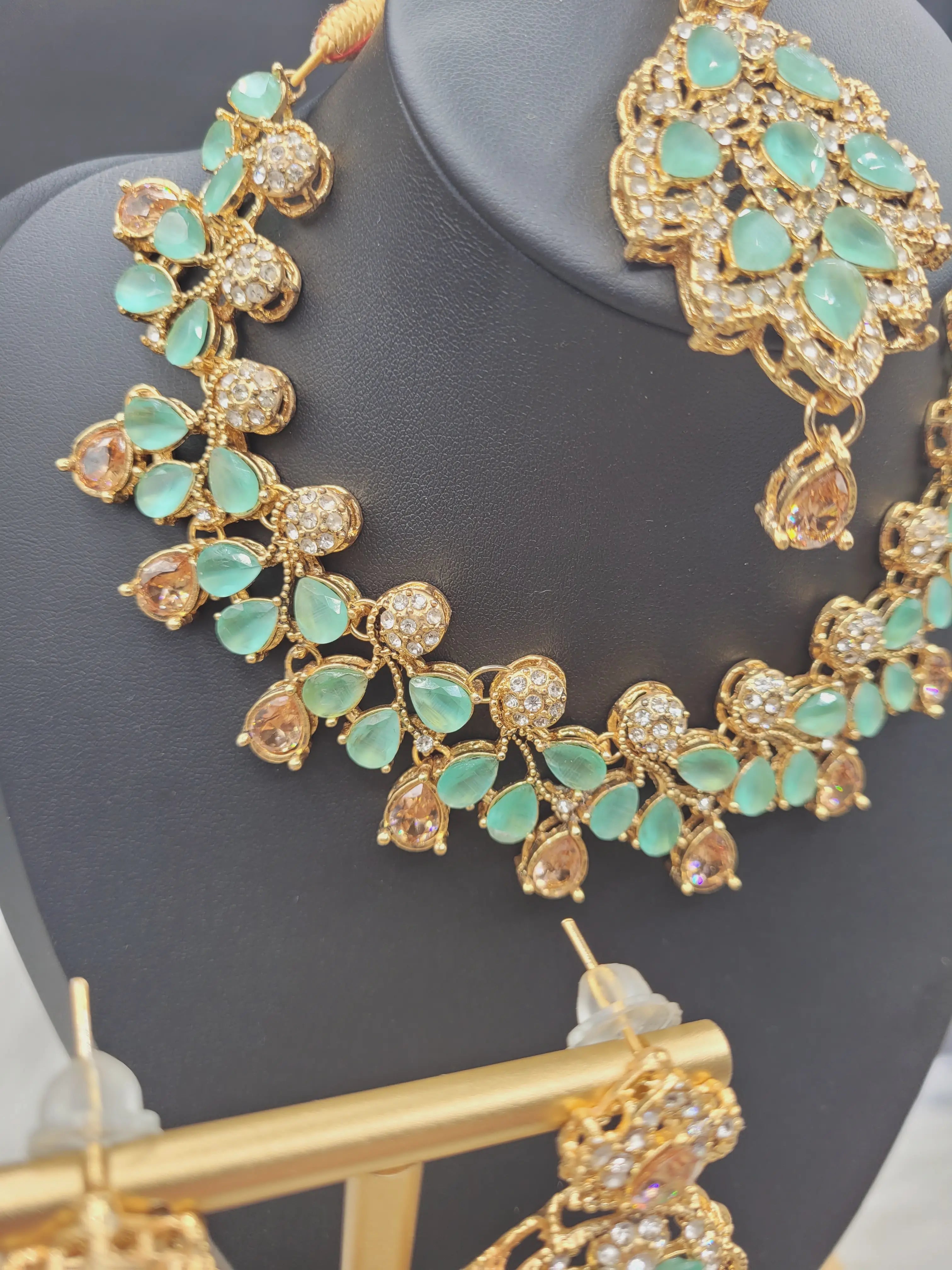 Angled side view of JV20 mint green necklace with gold-plated setting and gemstone detailing.