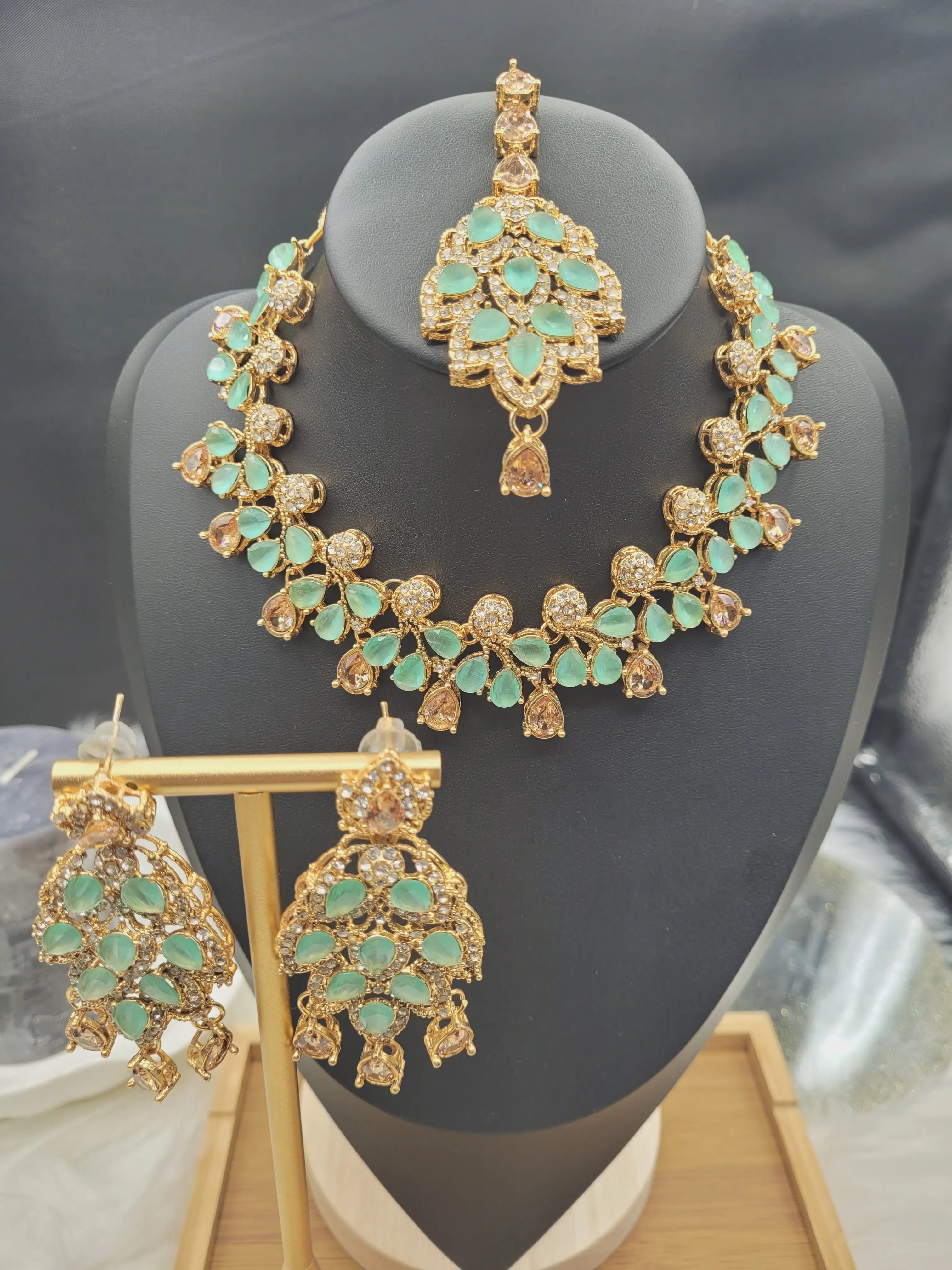 JV20 mint green necklace set with earrings and tikka displayed on black jewelry stand