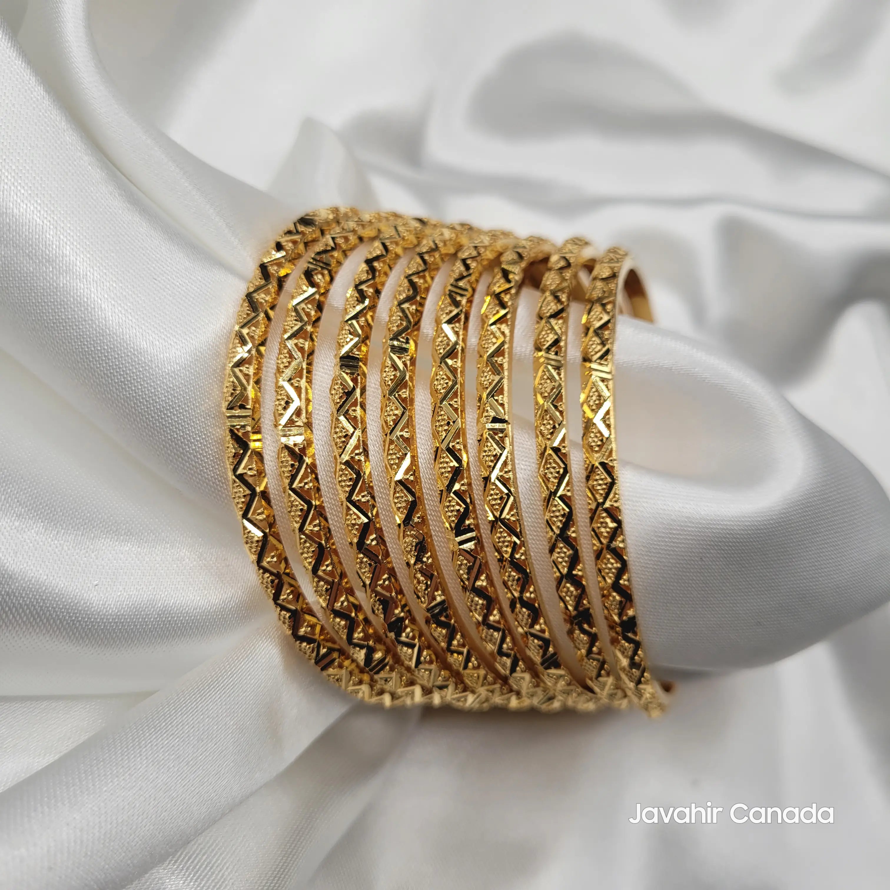 JV3031 gold plated bangle set of 8 displayed on white satin