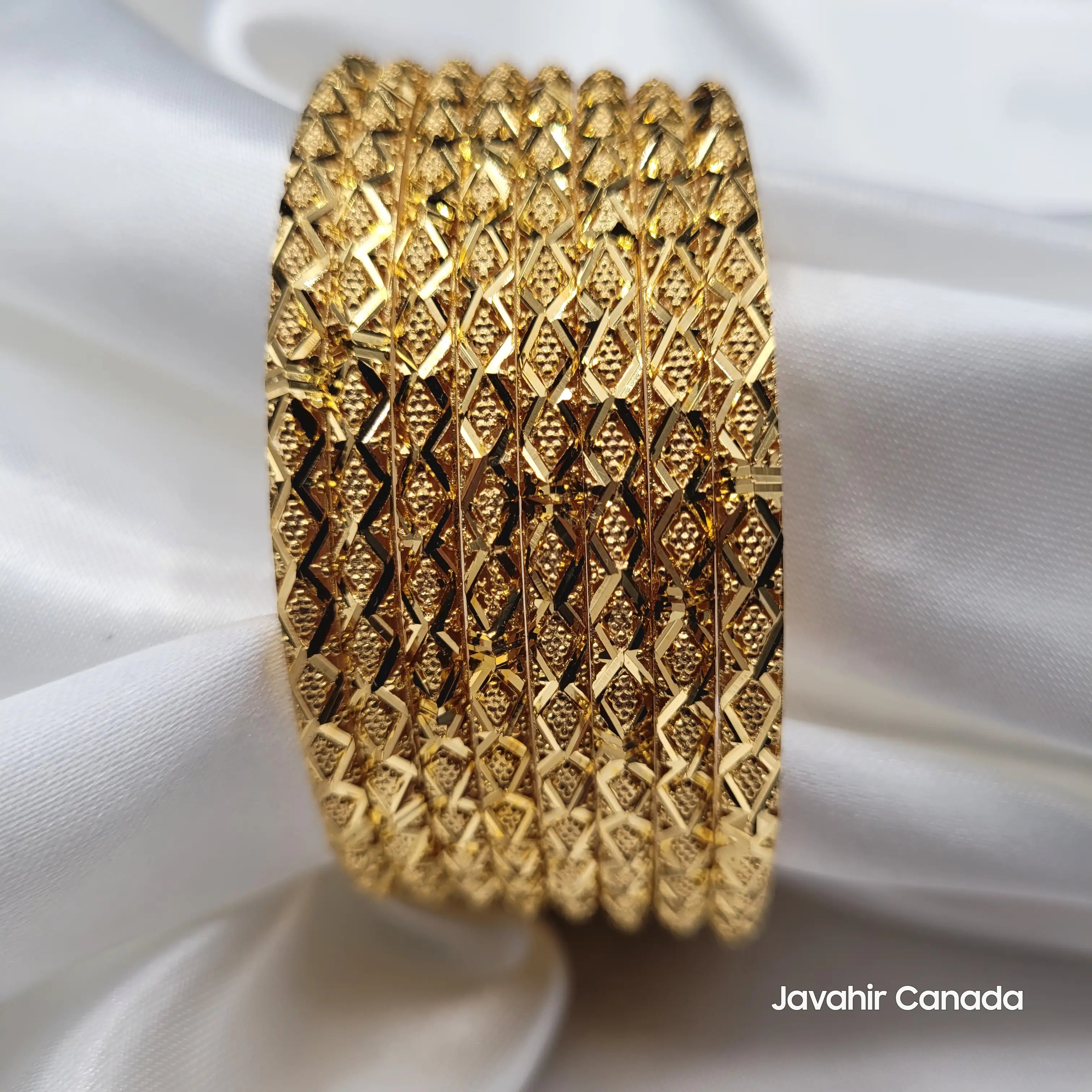 Stack of 8 gold bangles with diamond-cut zigzag texture and 22K shine