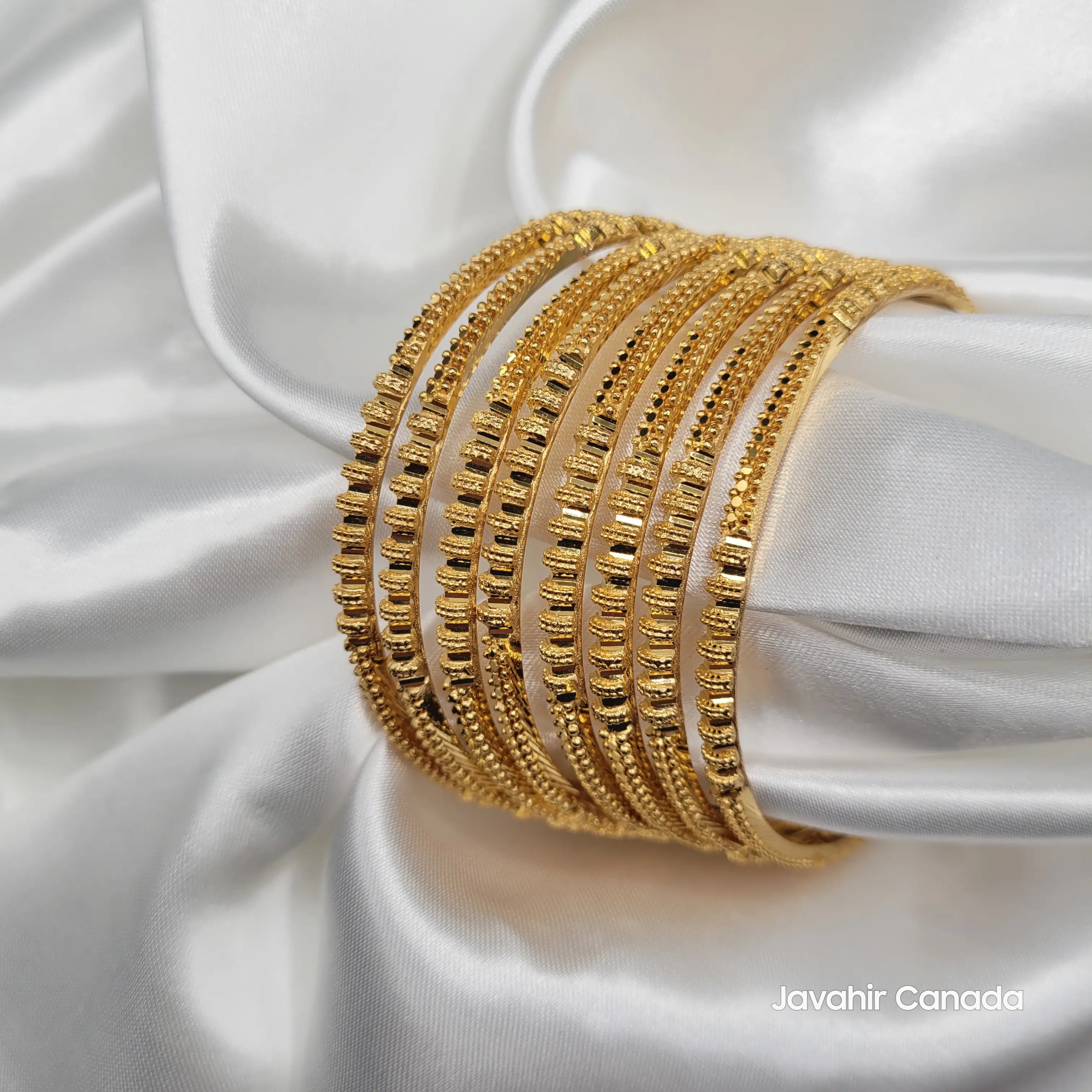 JV3033 gold plated bangles set with bar and bead design on white fabric