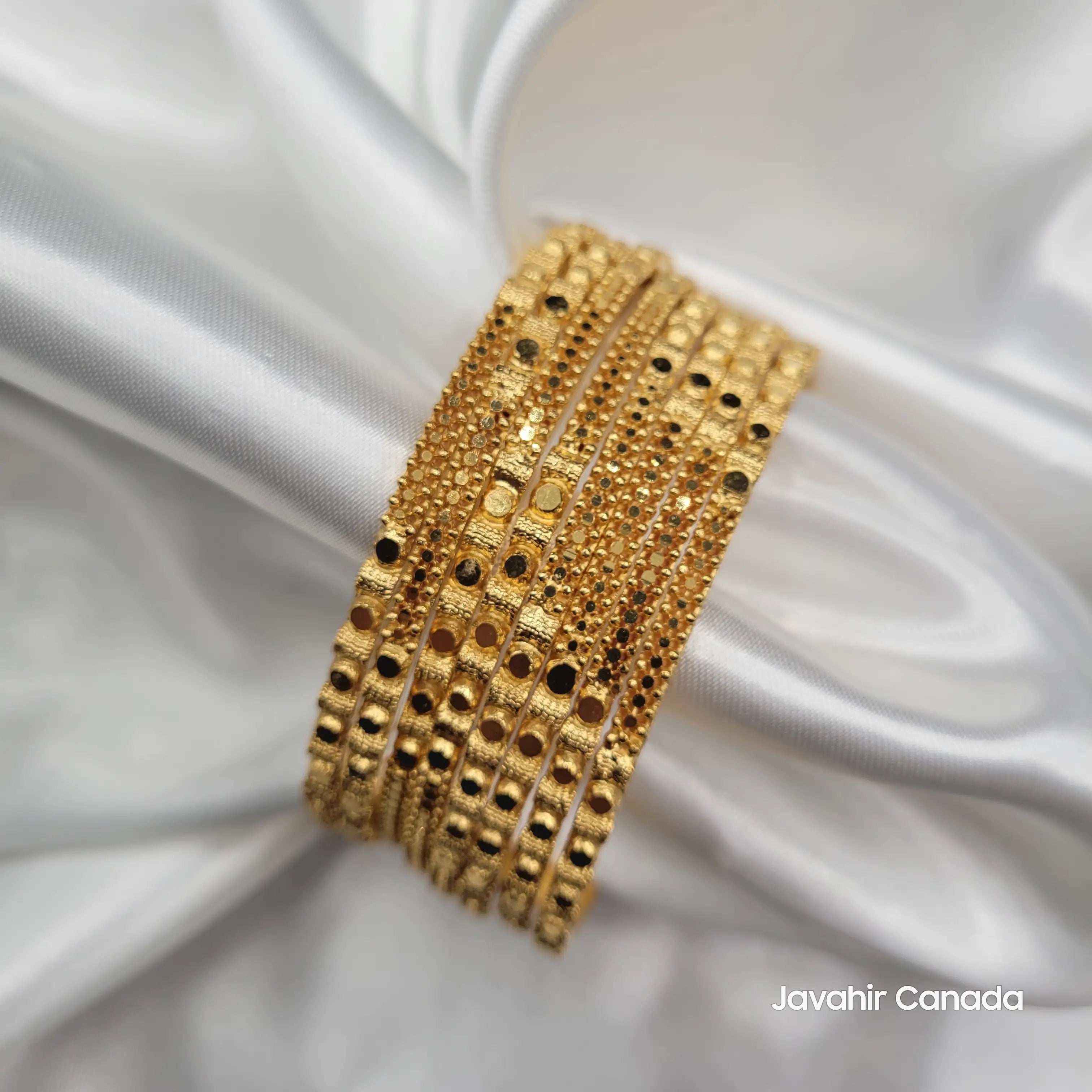Stack of gold bangles featuring reflective finish and fine beaded patterns