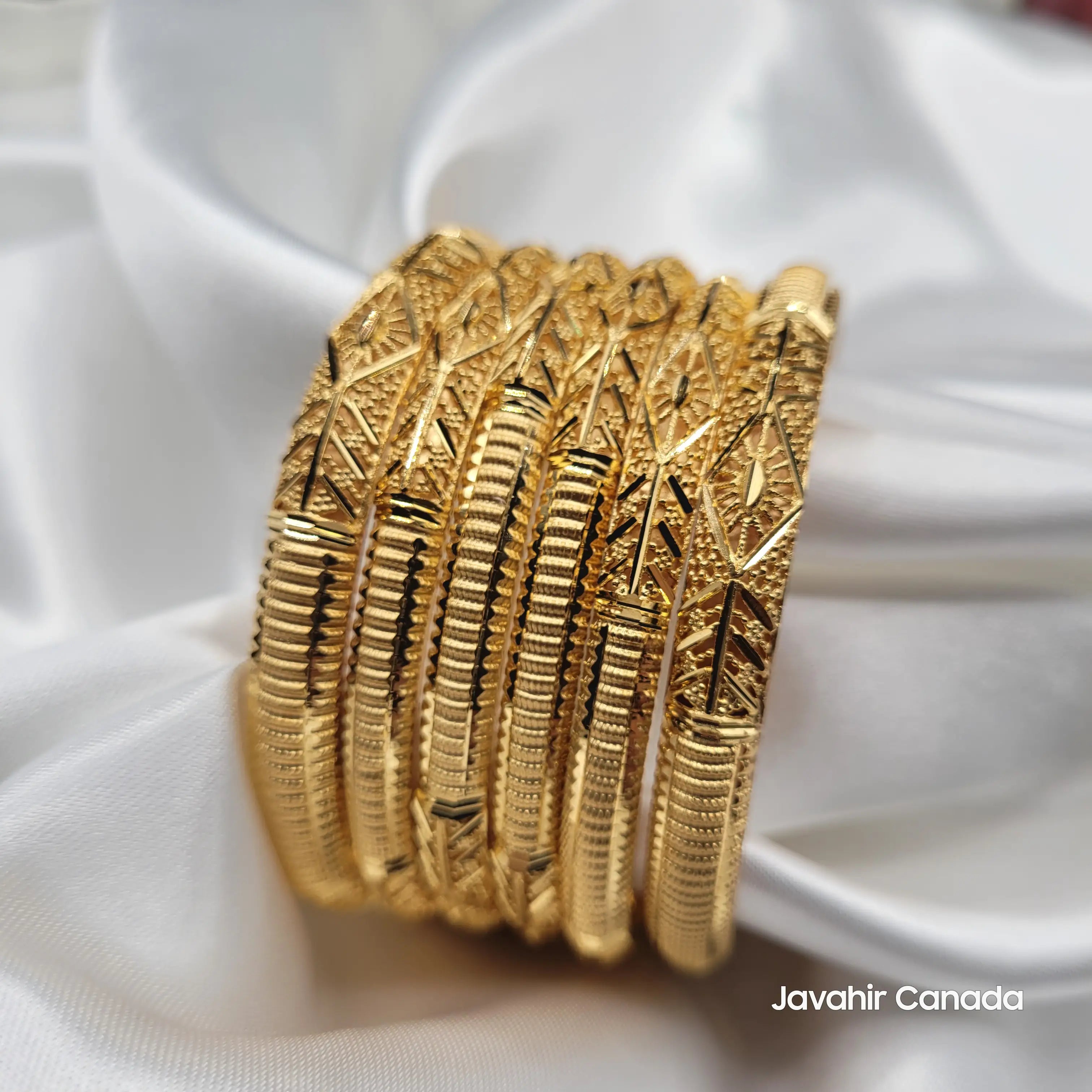 Set of 6 gold bangles with detailed geometric engraving on satin