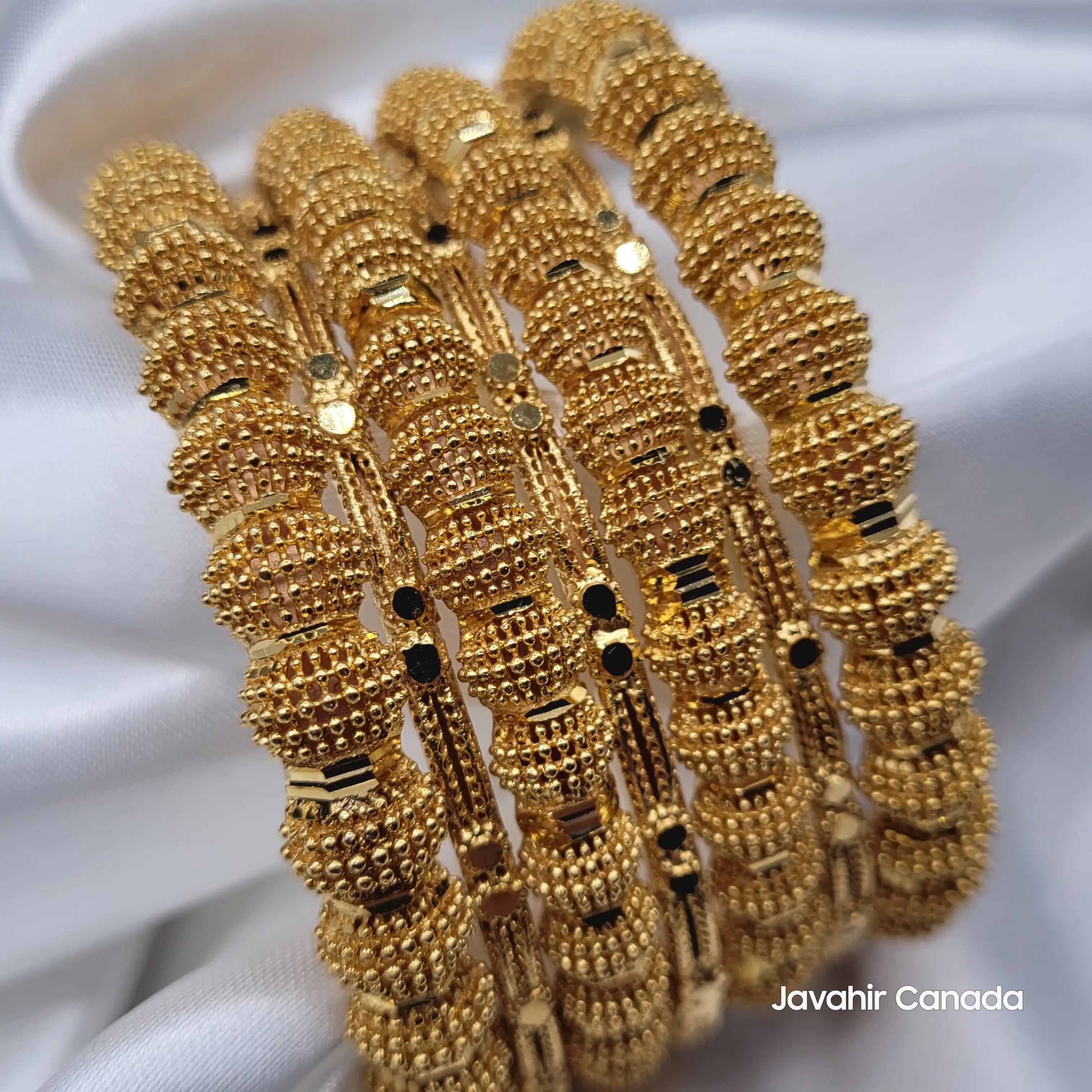 Close-up of JV3040 gold bangles with rounded textured beads