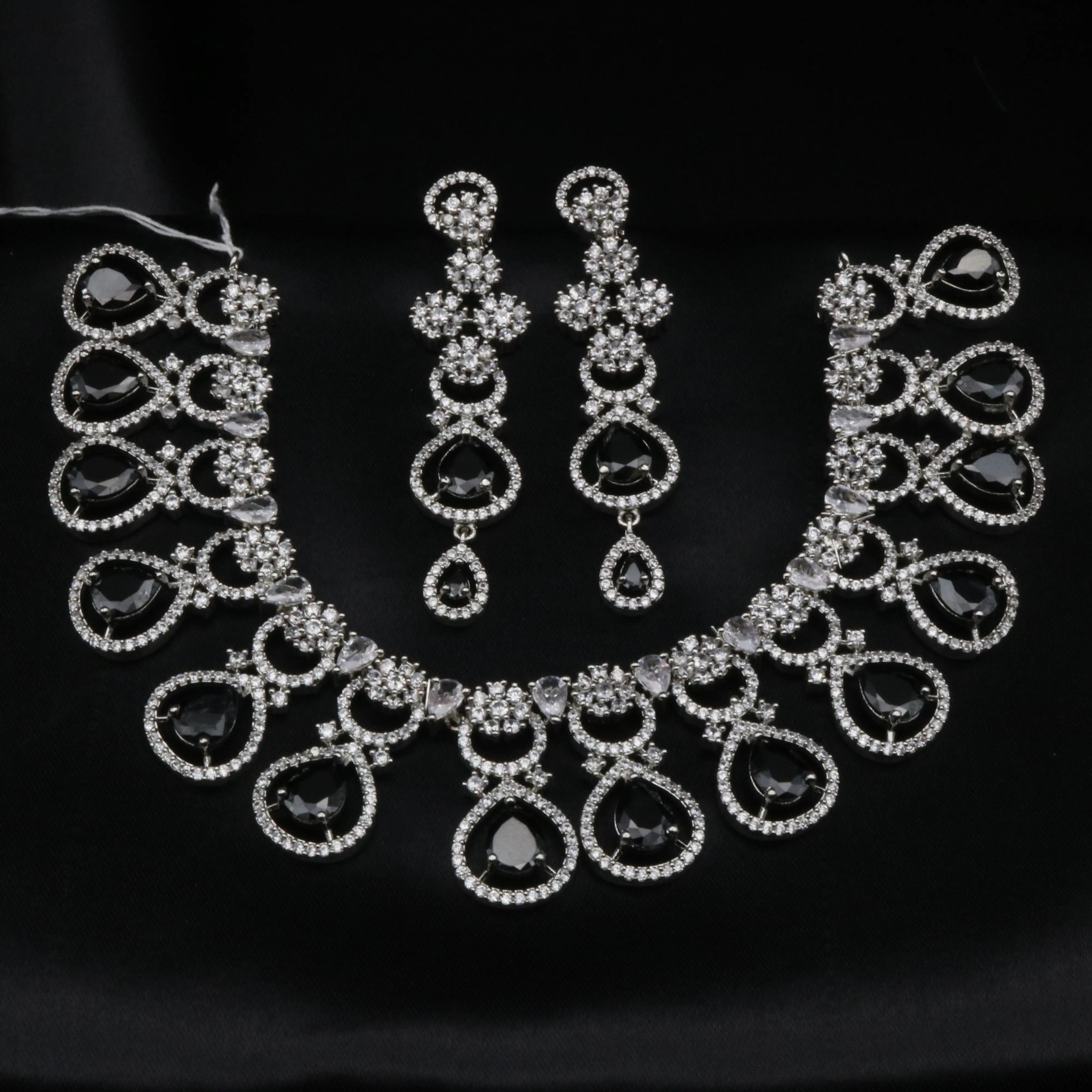 Full black teardrop CZ necklace set with silver-tone base and matching earrings displayed on black fabric.