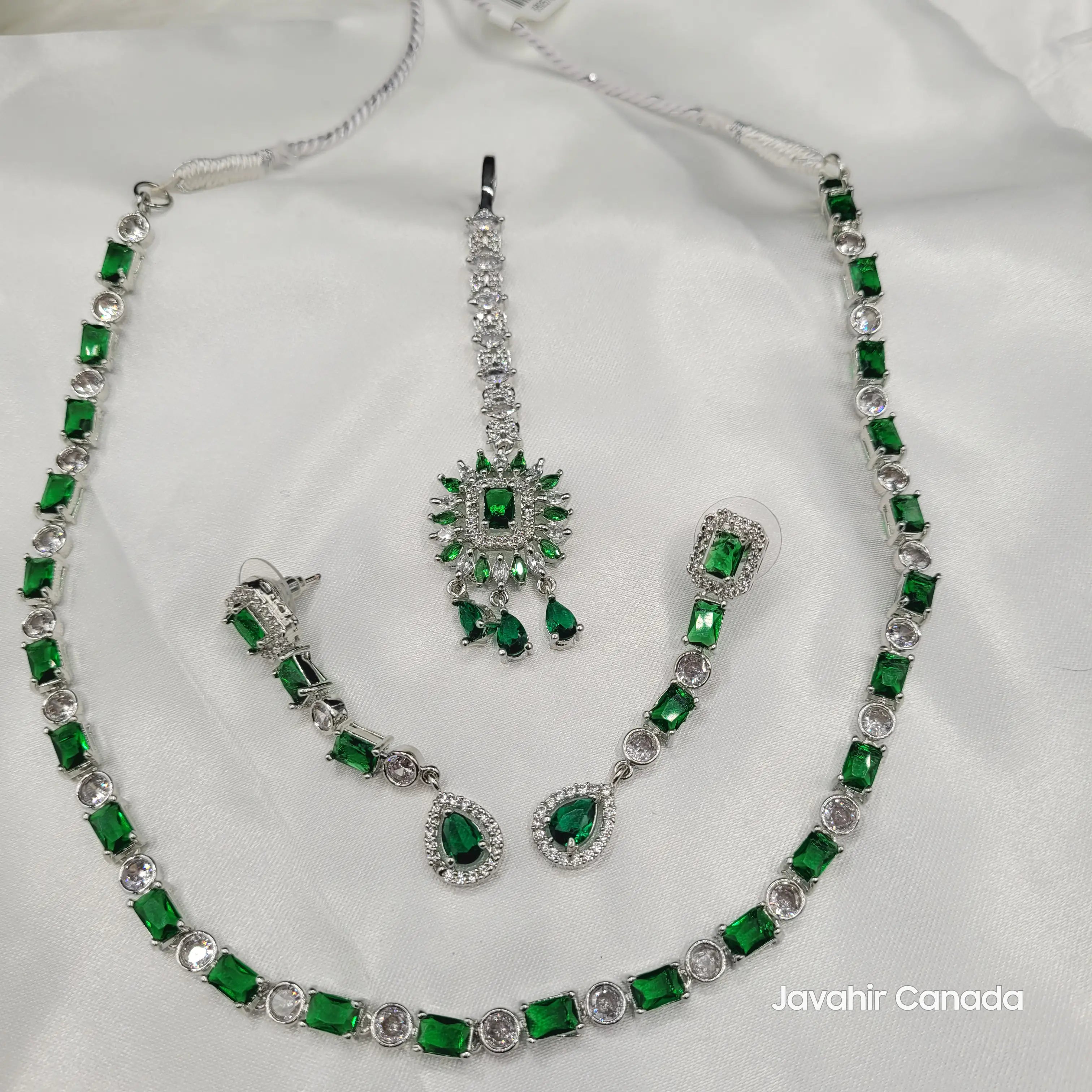 Flat lay of Luna necklace set featuring emerald-cut green zircon stones and American diamonds on silver-tone base.