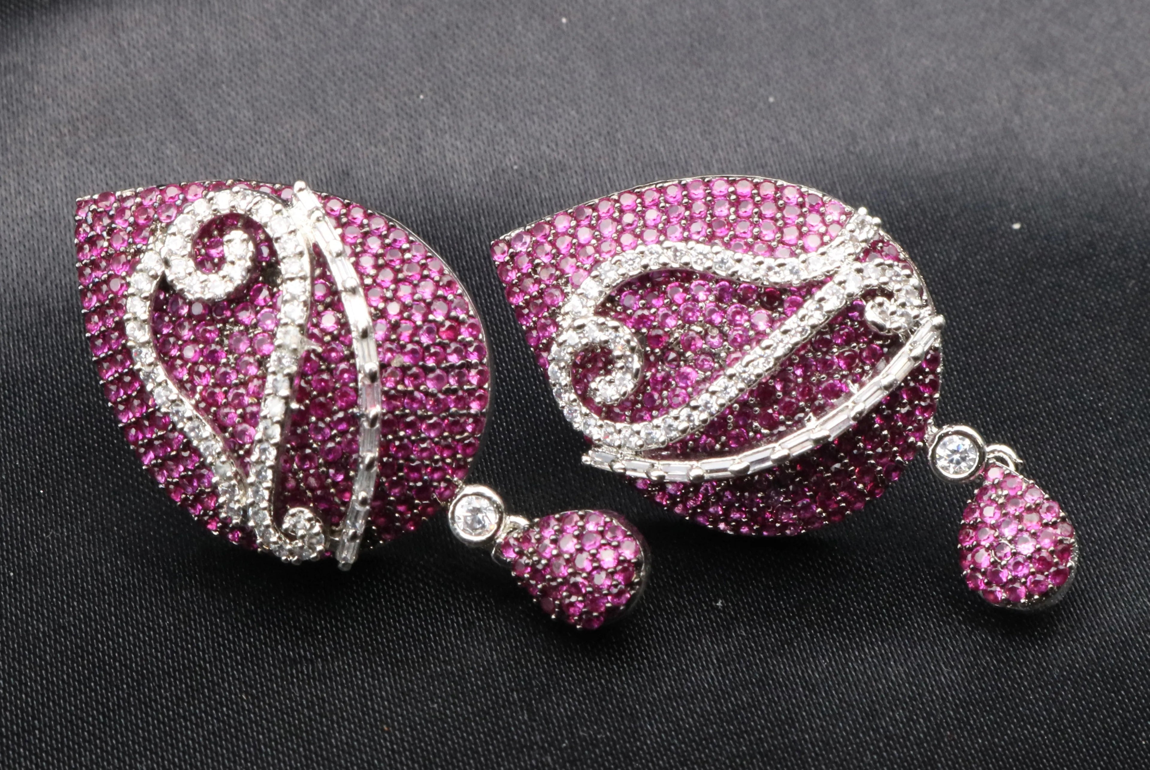 Pair of pink and silver American diamonds earrings on a black background