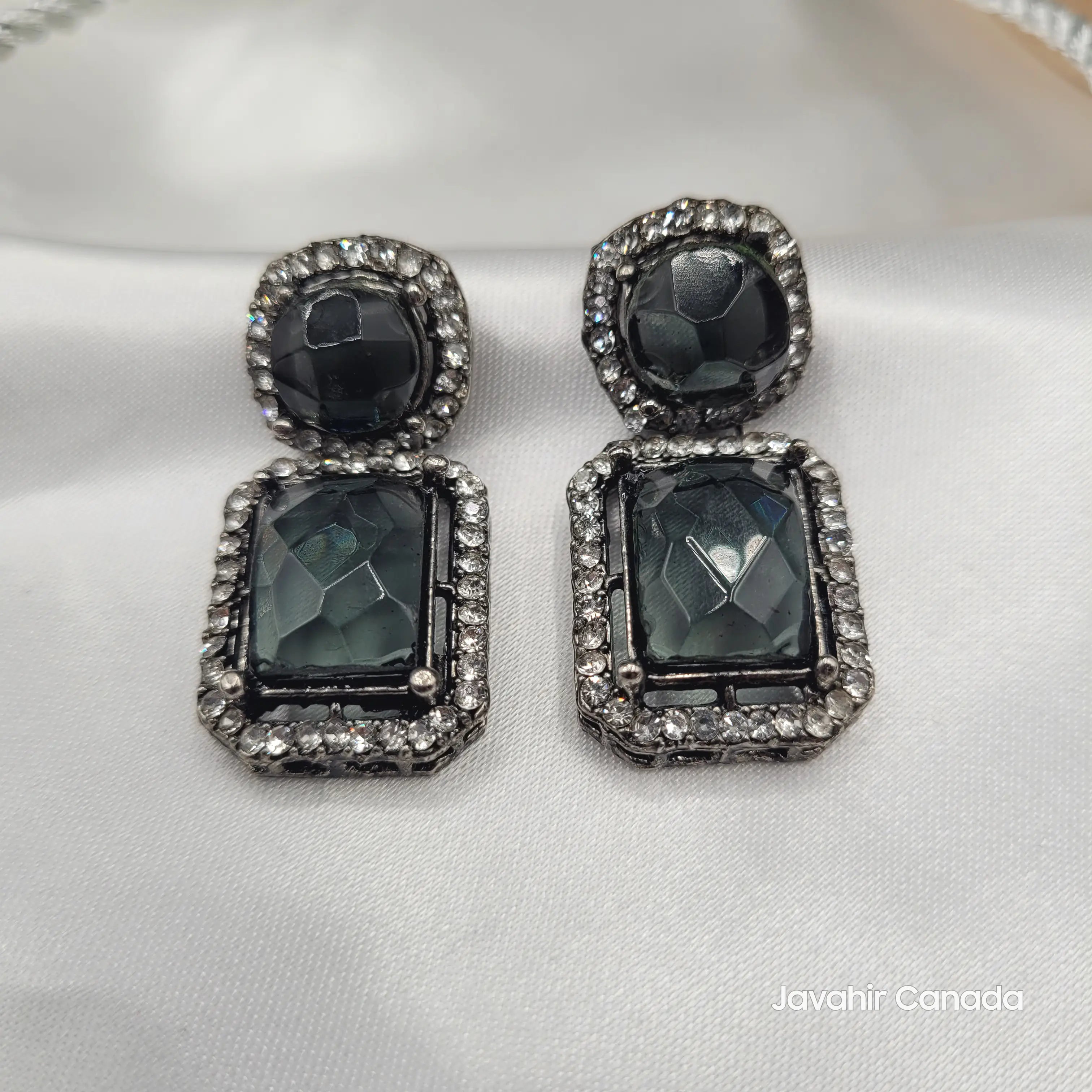 Close-up of Maharaj black onyx look earrings with faceted stones and CZ border on satin