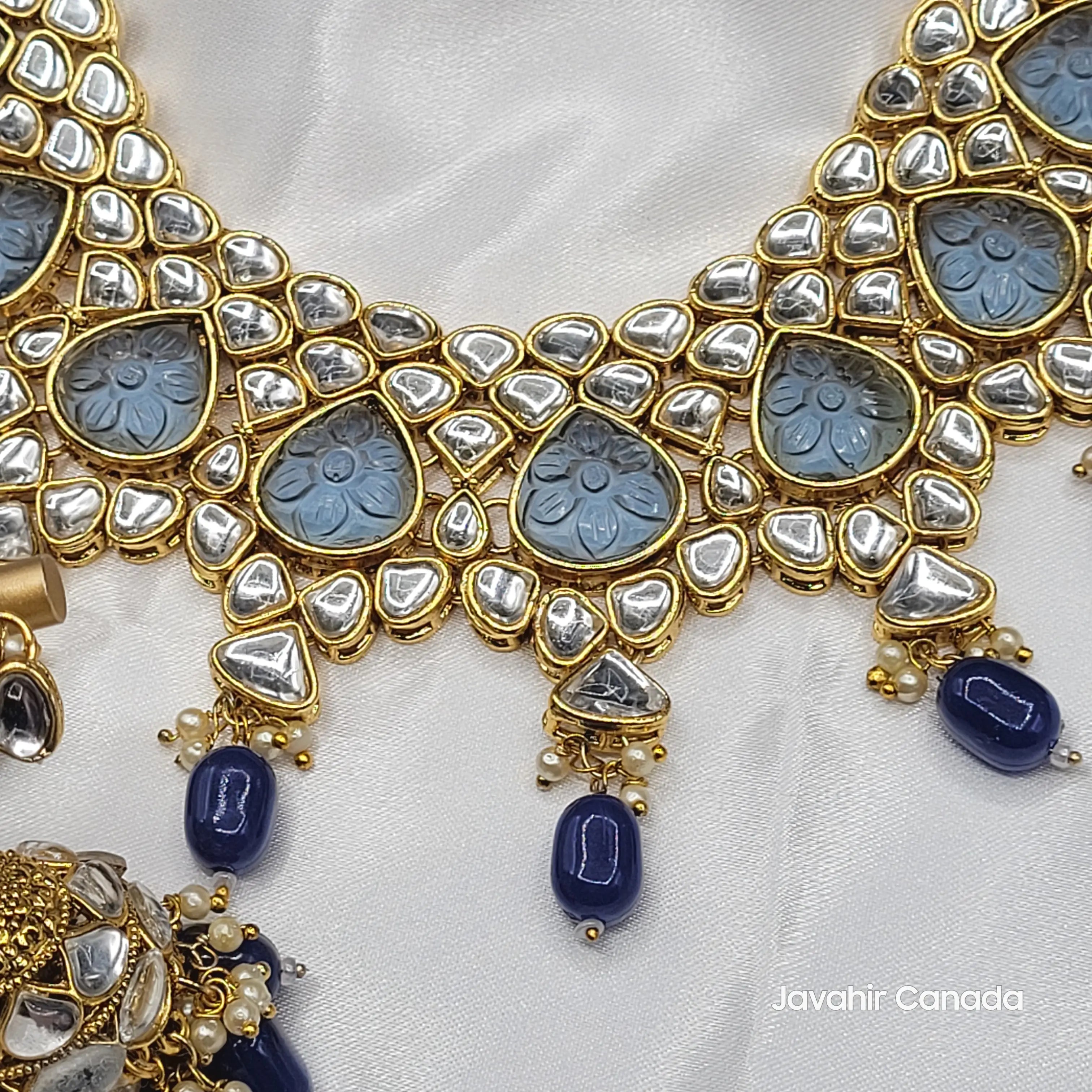 Zoomed-in look at Marina choker necklace with blue carved glass stones and teardrop kundan work on a gold frame