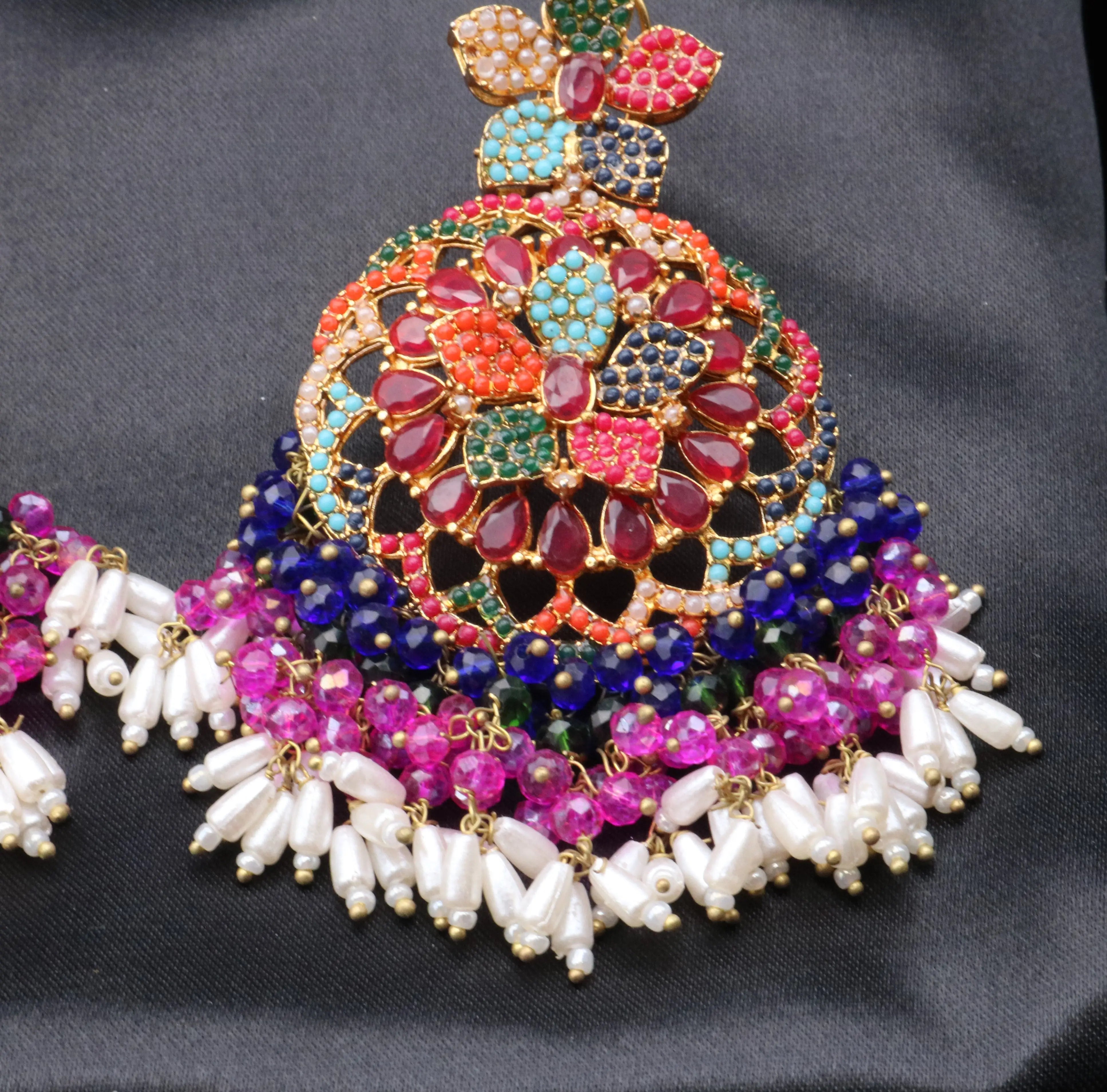 A pair of colorful floral-style earrings displayed on a black background.