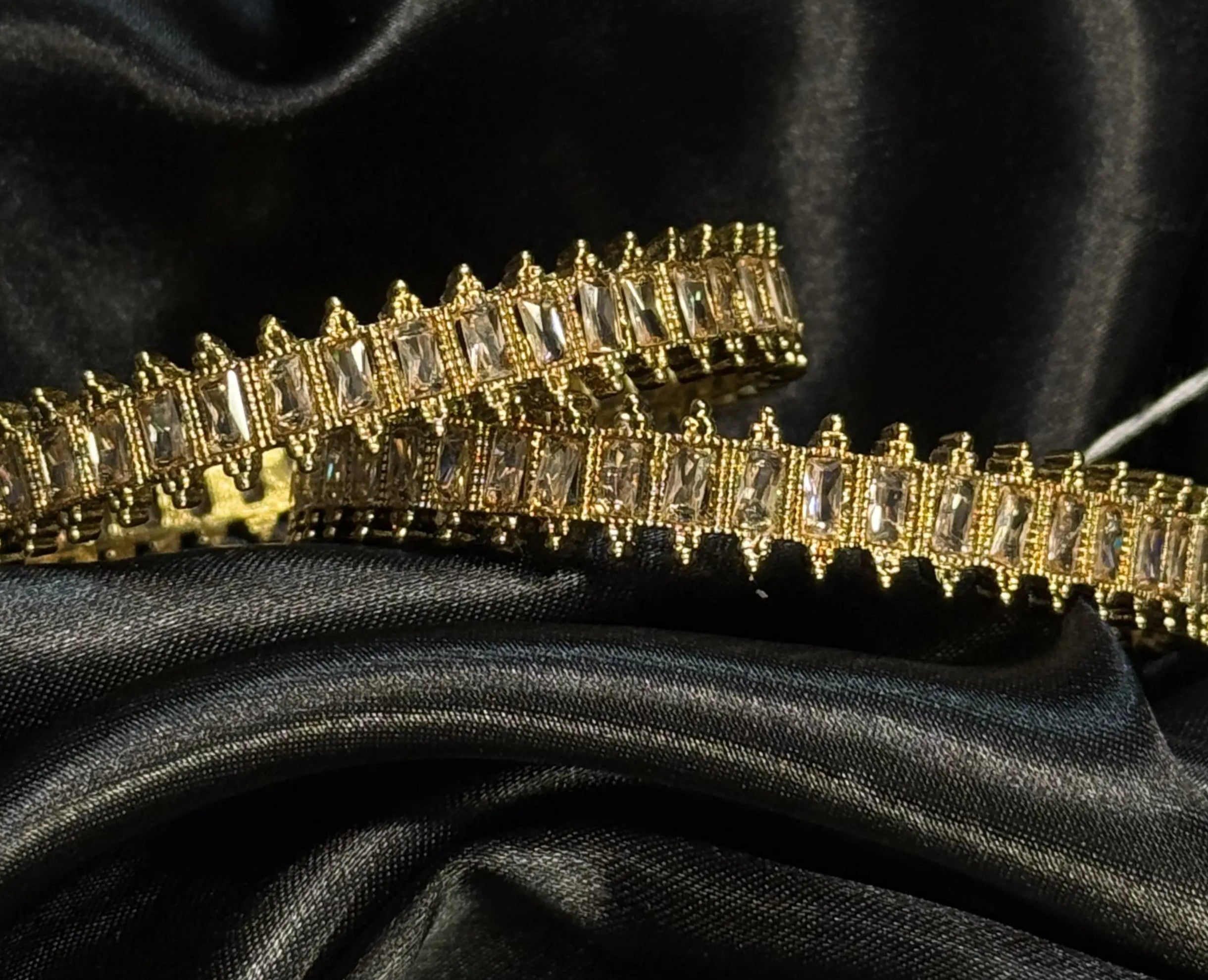 Gold bangles with clear stones on black satin fabric