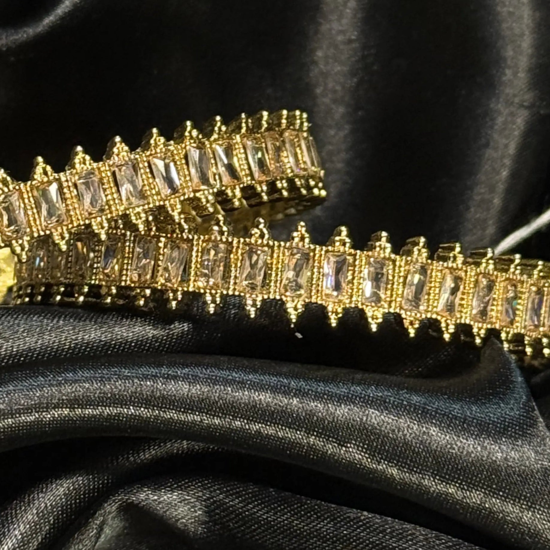 Gold bracelet with clear stones on black satin fabric