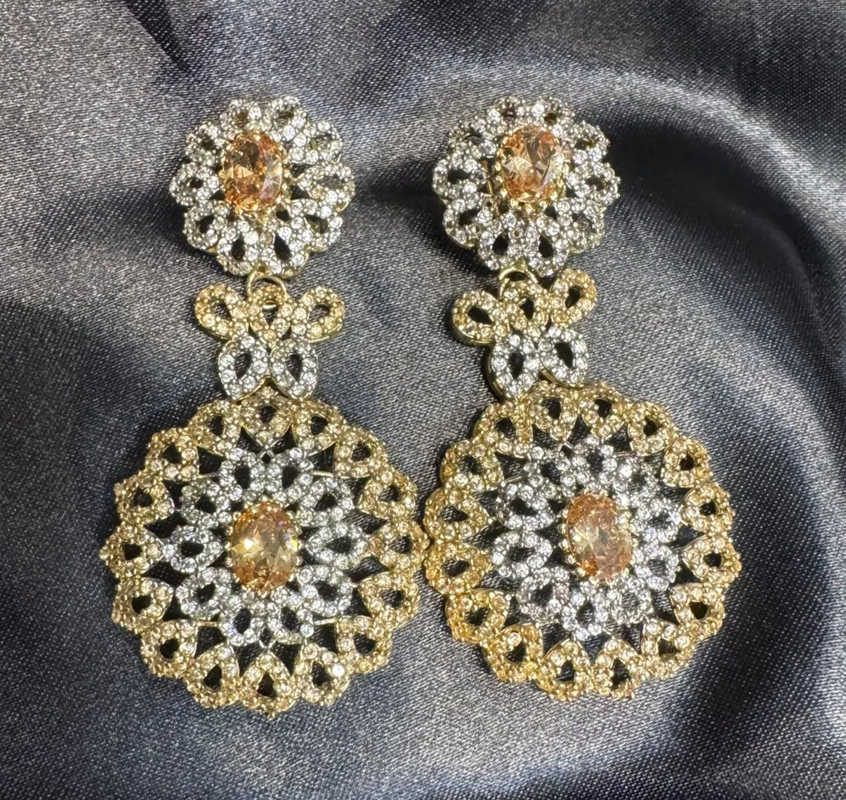 Pair of gold and silver earrings on a gray fabric background
