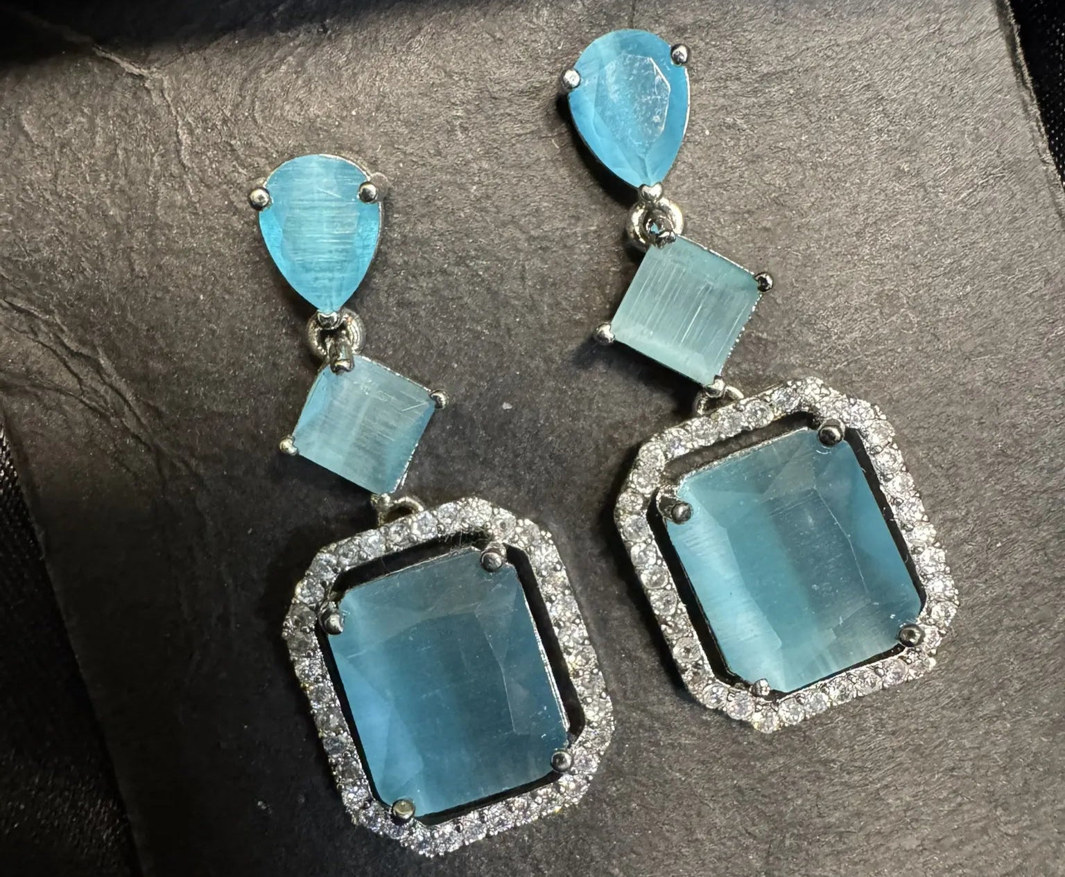 Pair of earrings with blue gemstones on a dark background