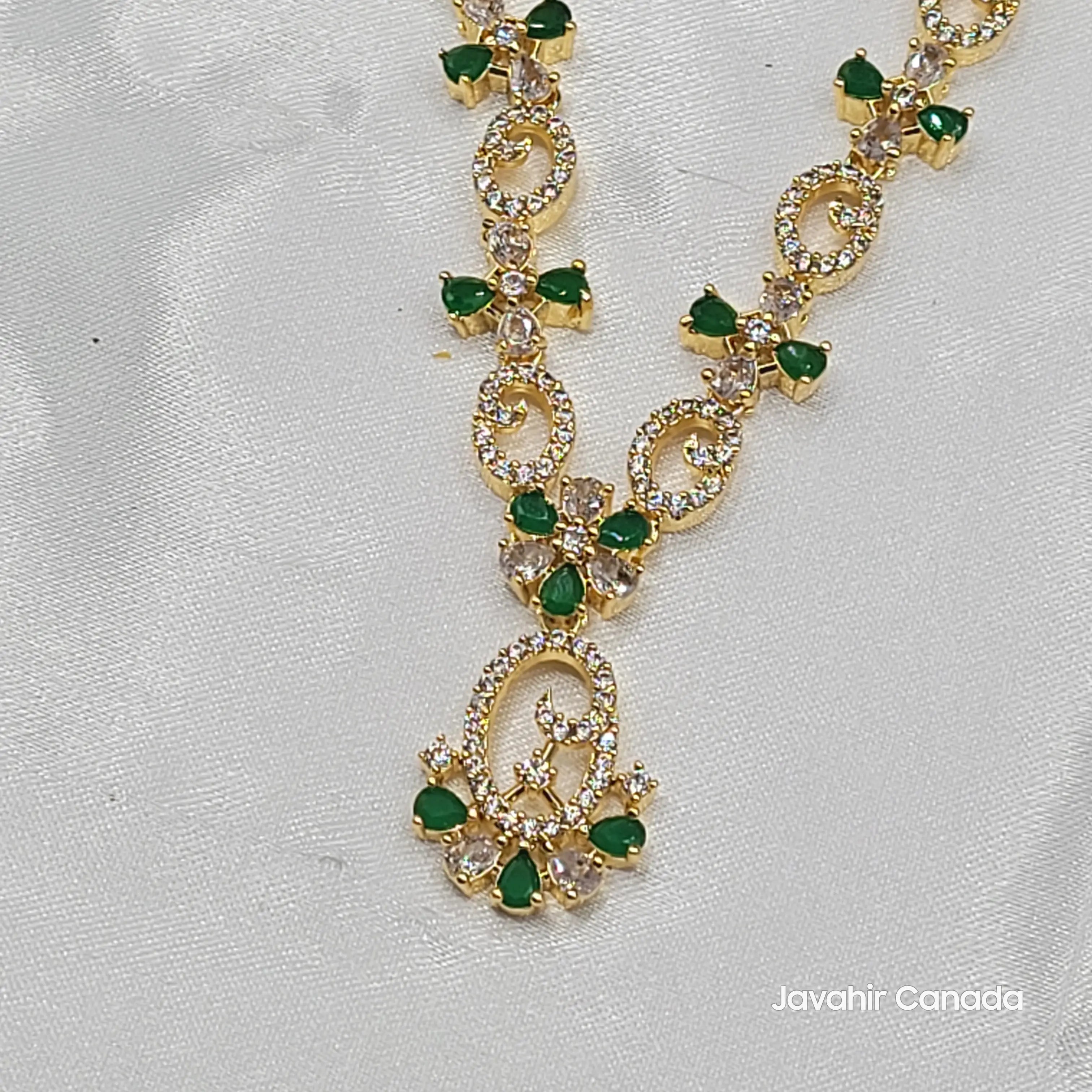 Close-up of Primrose pendant detailing with green stones and gold-plated loop elements.