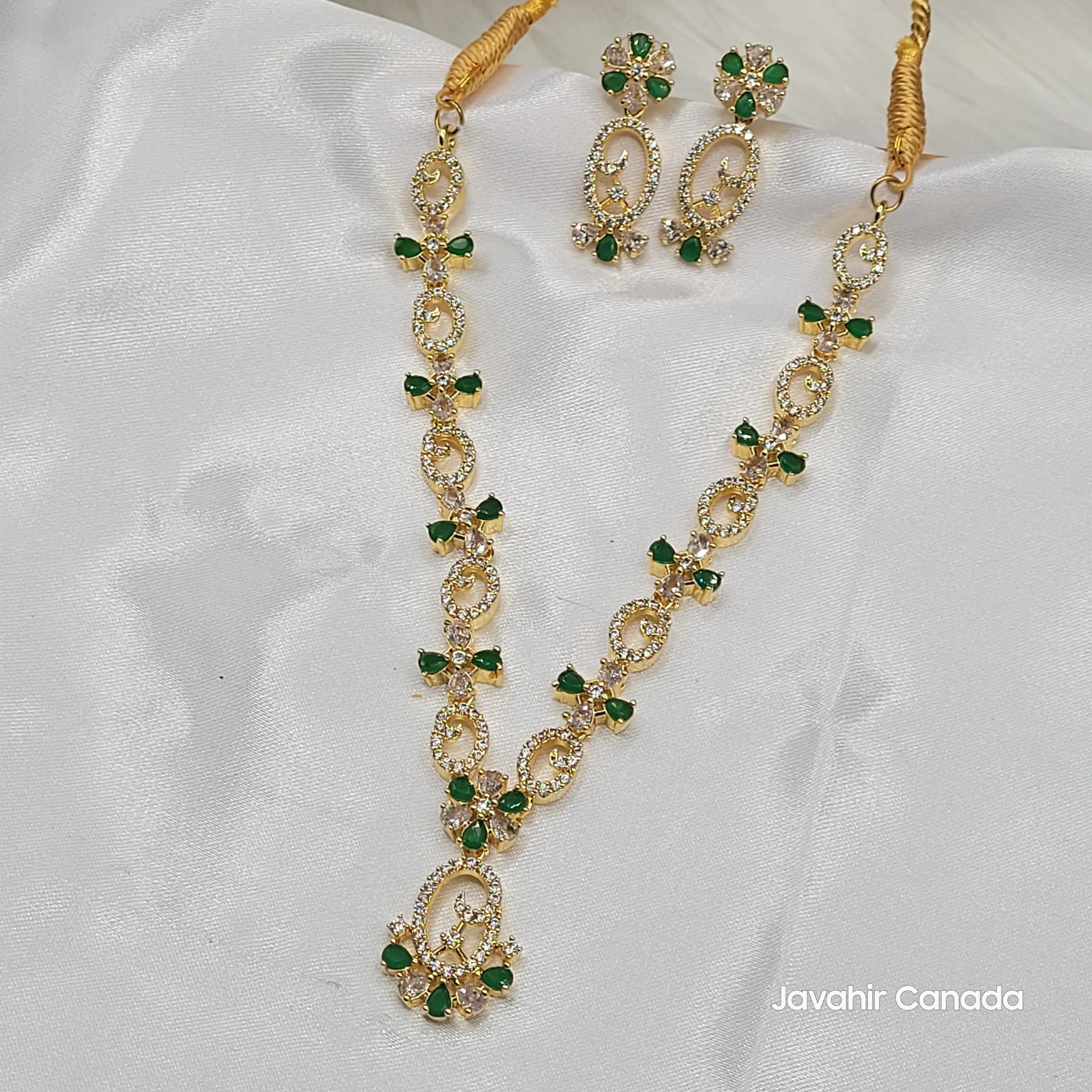 Primrose necklace set with green teardrop stones and floral CZ design on white fabric background.