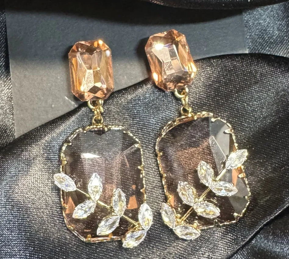 Pair of ornate earrings on a black satin surface