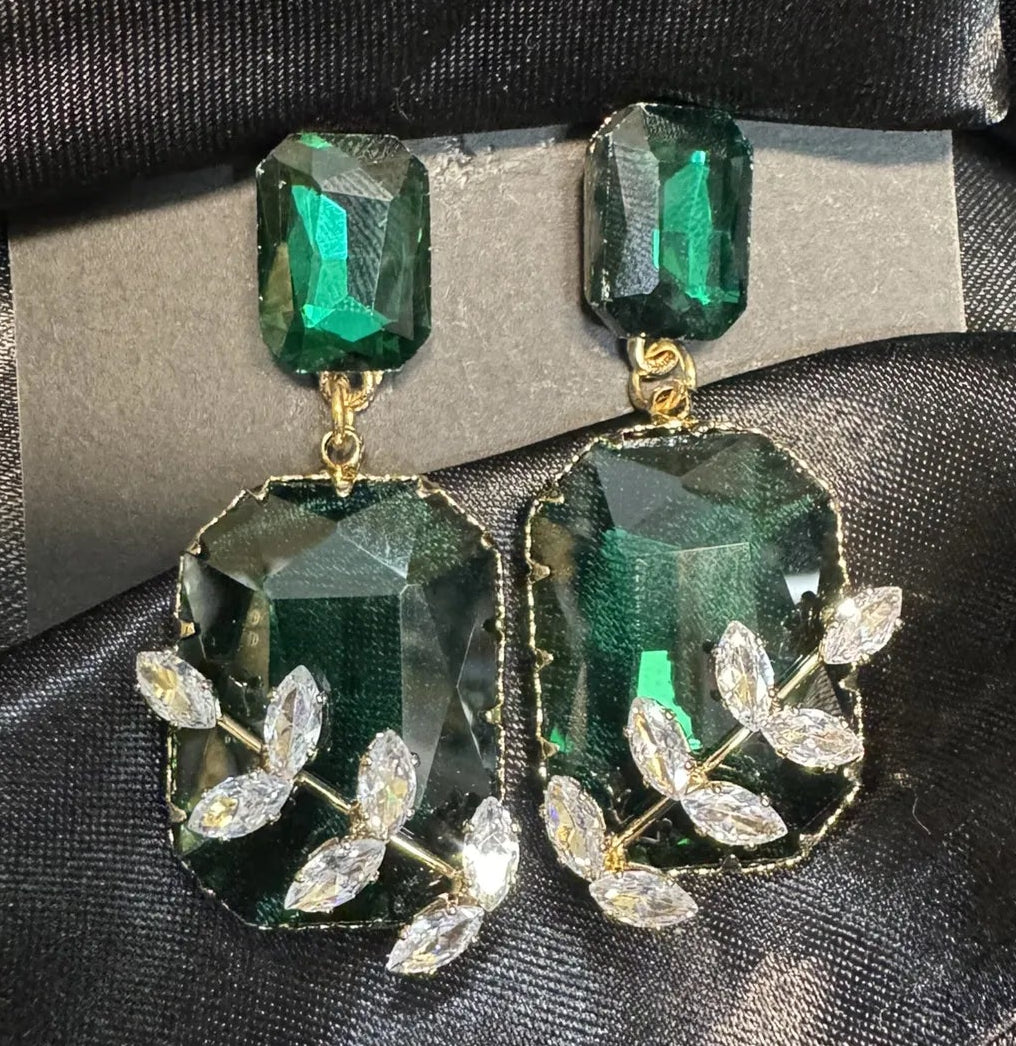 Green gemstone earrings with leaf details on a black satin background