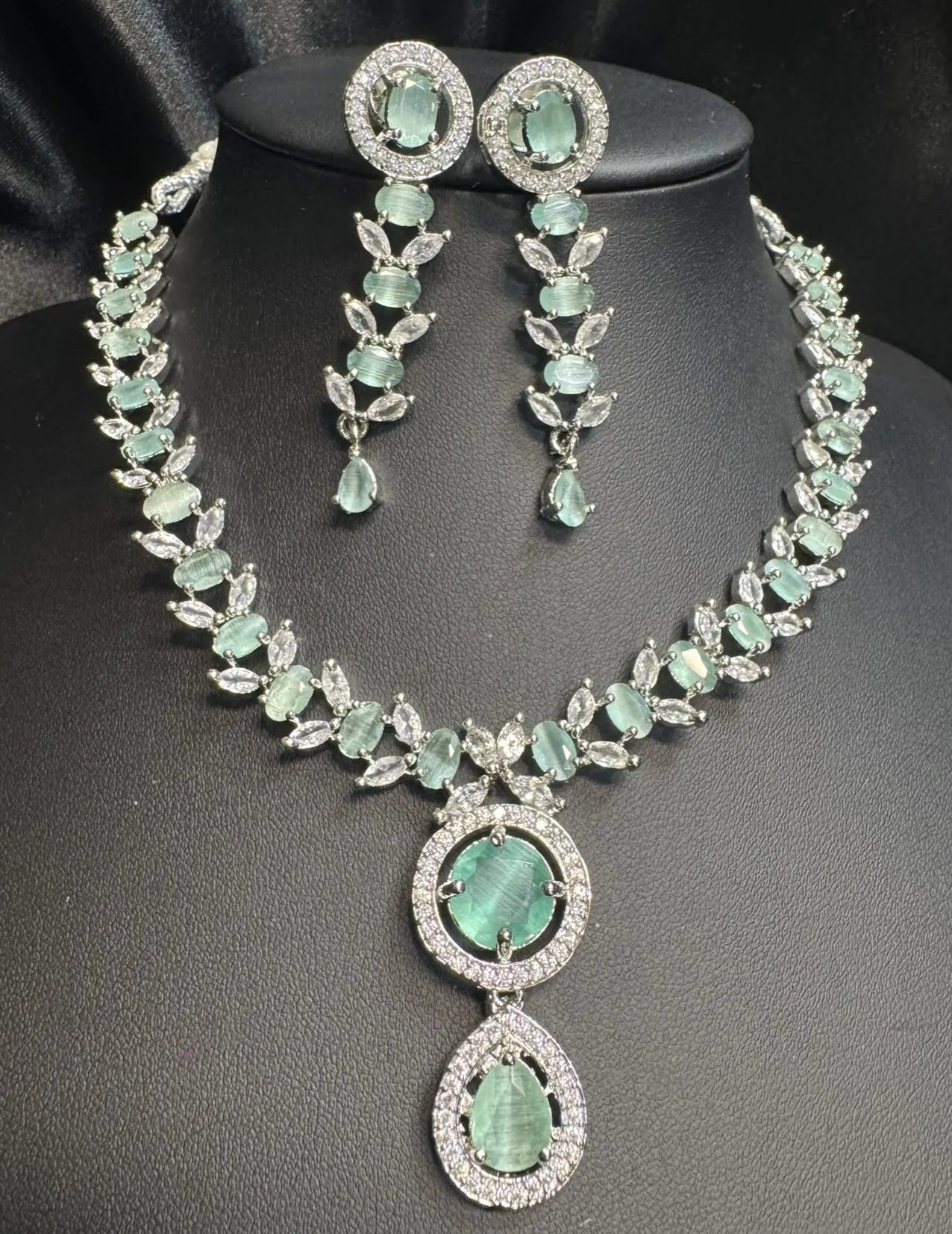 Teal necklace and earrings on a black mannequin