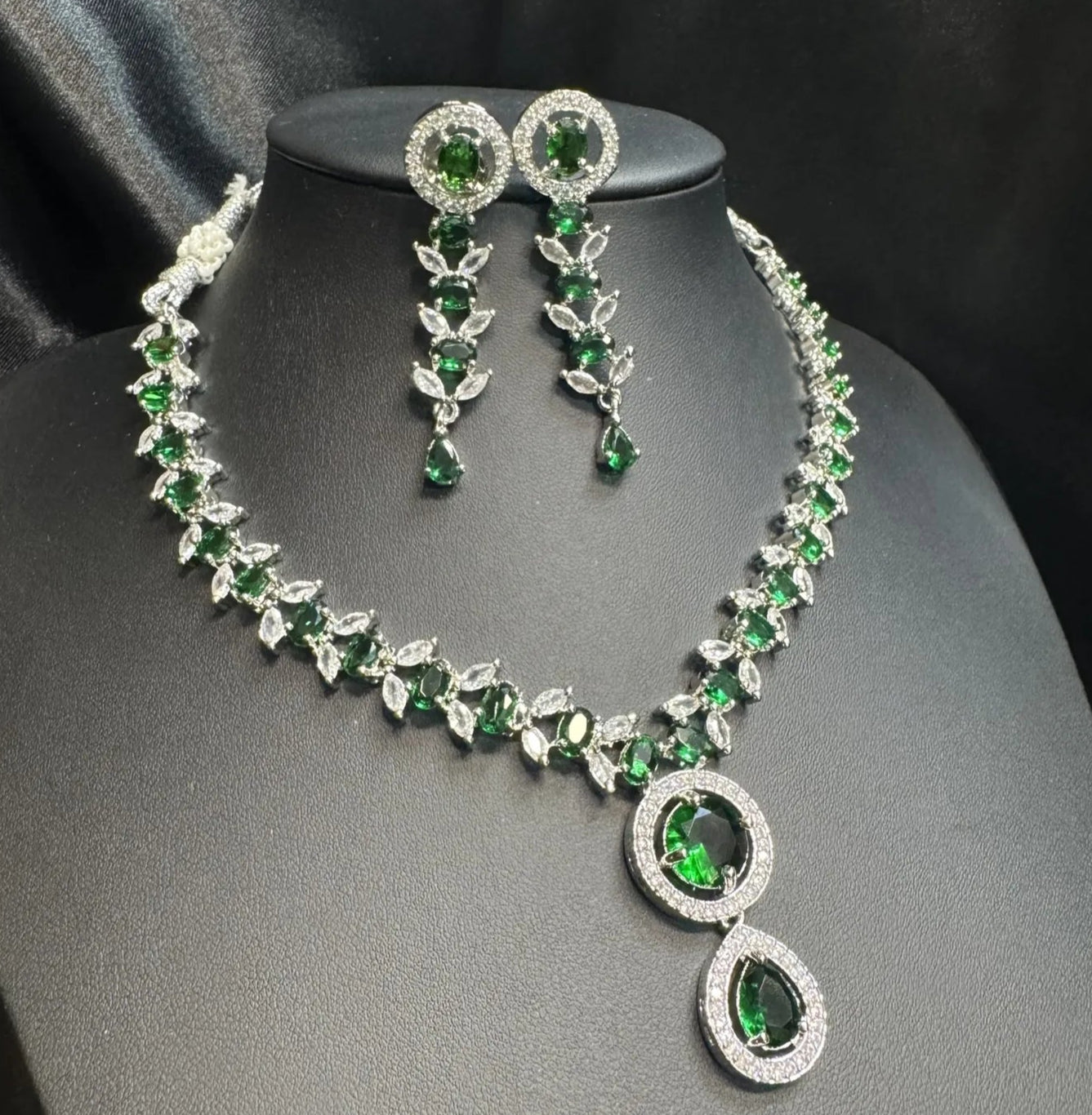 Jewelry set with necklace and earrings featuring green gemstones on a black background