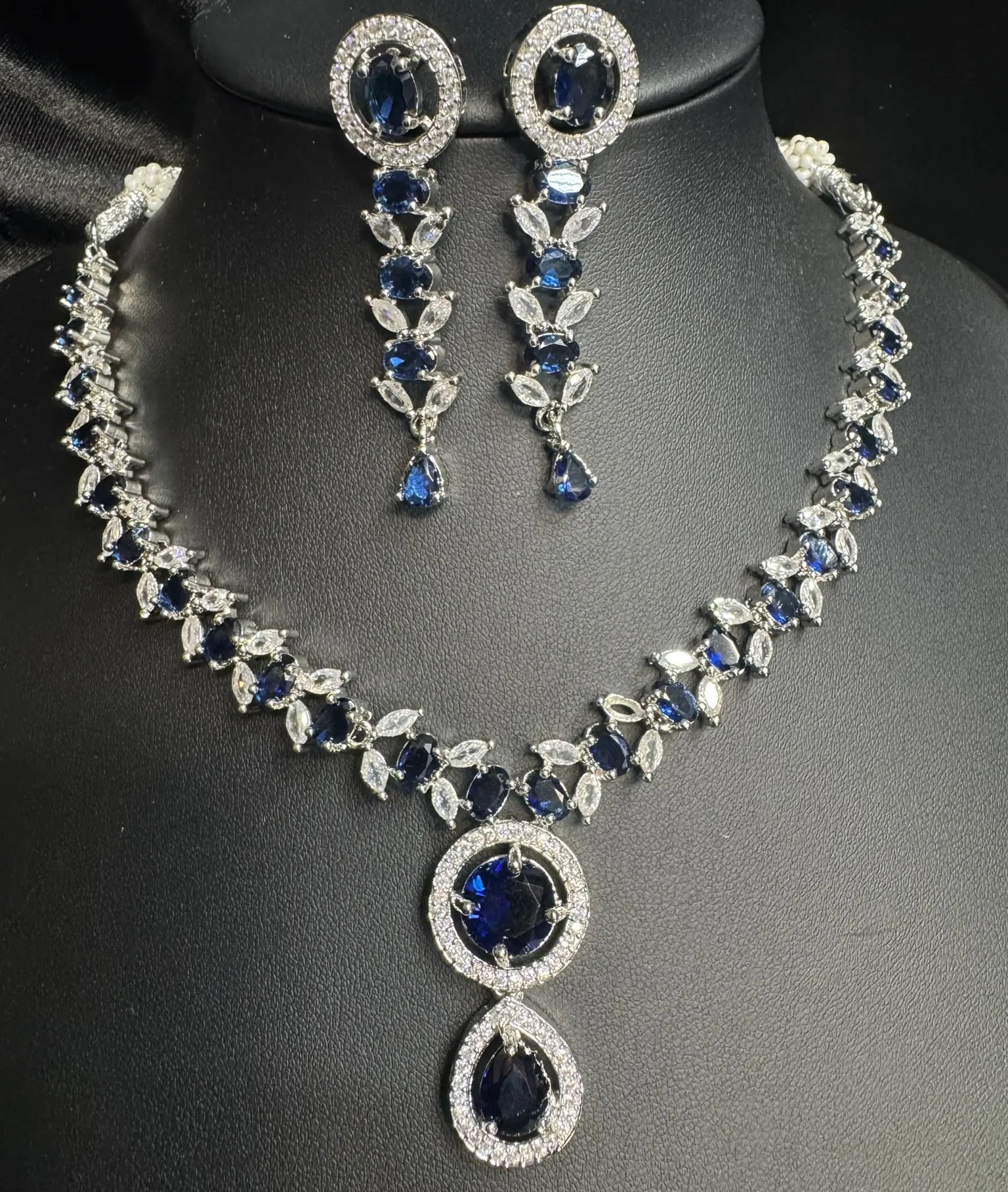 Jewelry set with necklace and earrings featuring blue stones on a black background