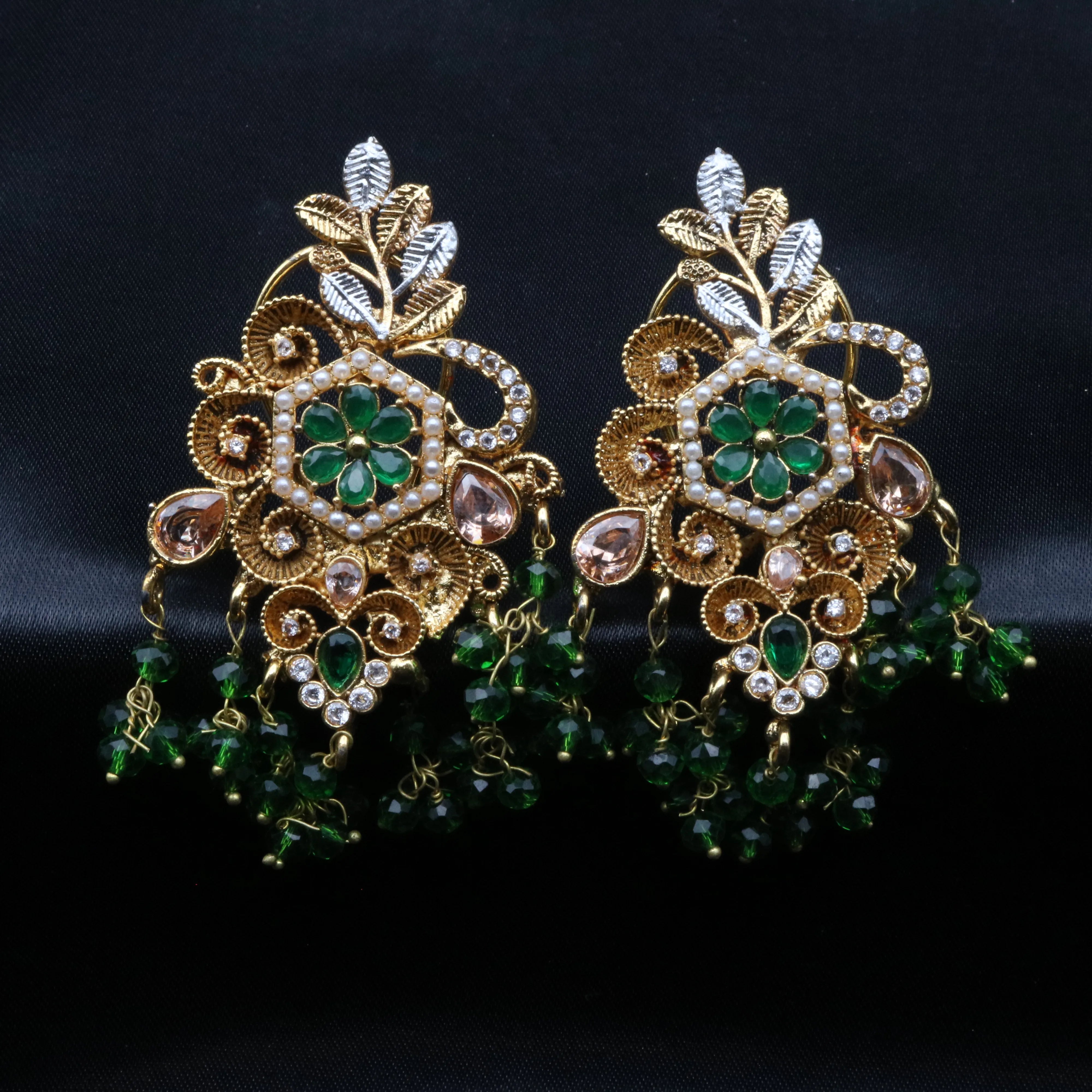 Pair of gold and green earrings on a black background