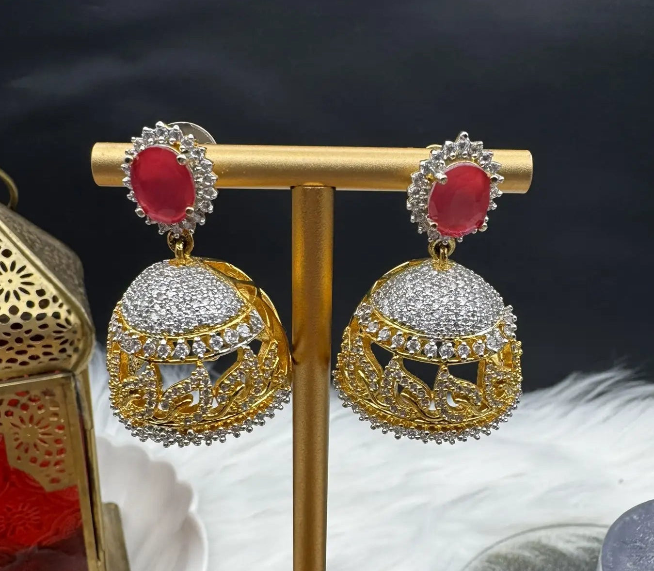 Goldplated and nano zarcon Pakistani style jhumka earrings with hotpink gemstones on a gold stand against a dark background. Jarao based design 