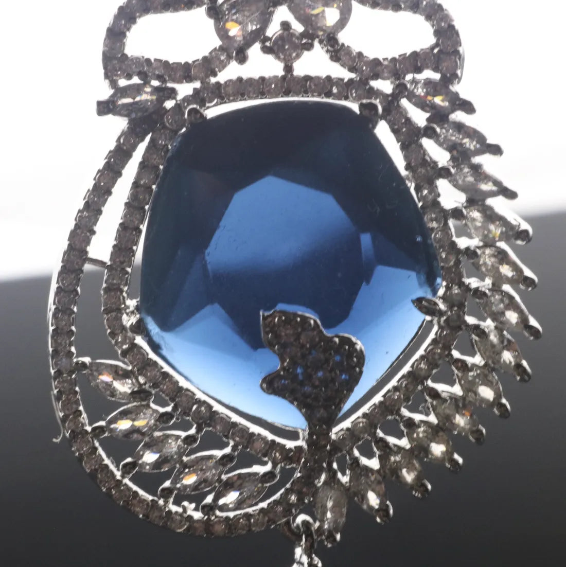 Jewelry with a blue gemstone and intricate metalwork on a white background