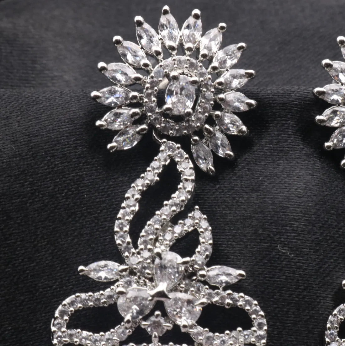 Close-up of a silver American diamonds earring with clear gemstones on a black background