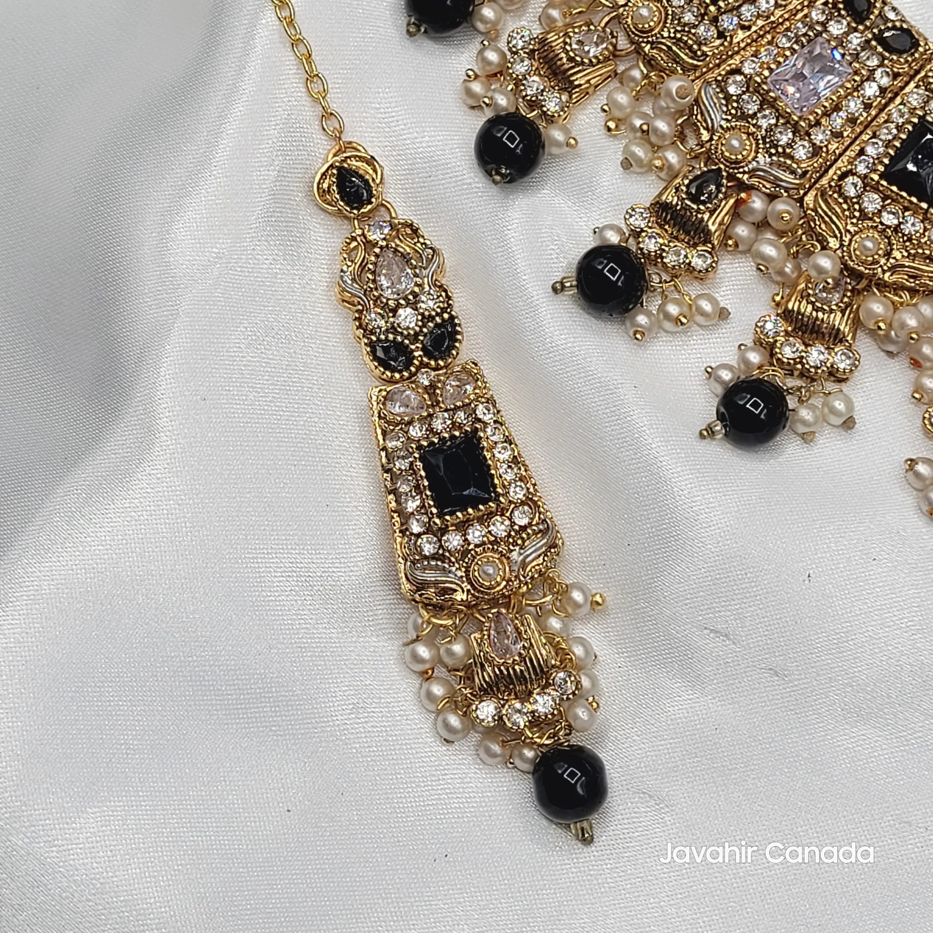 Ornate gold and black beaded teeka on a white fabric background