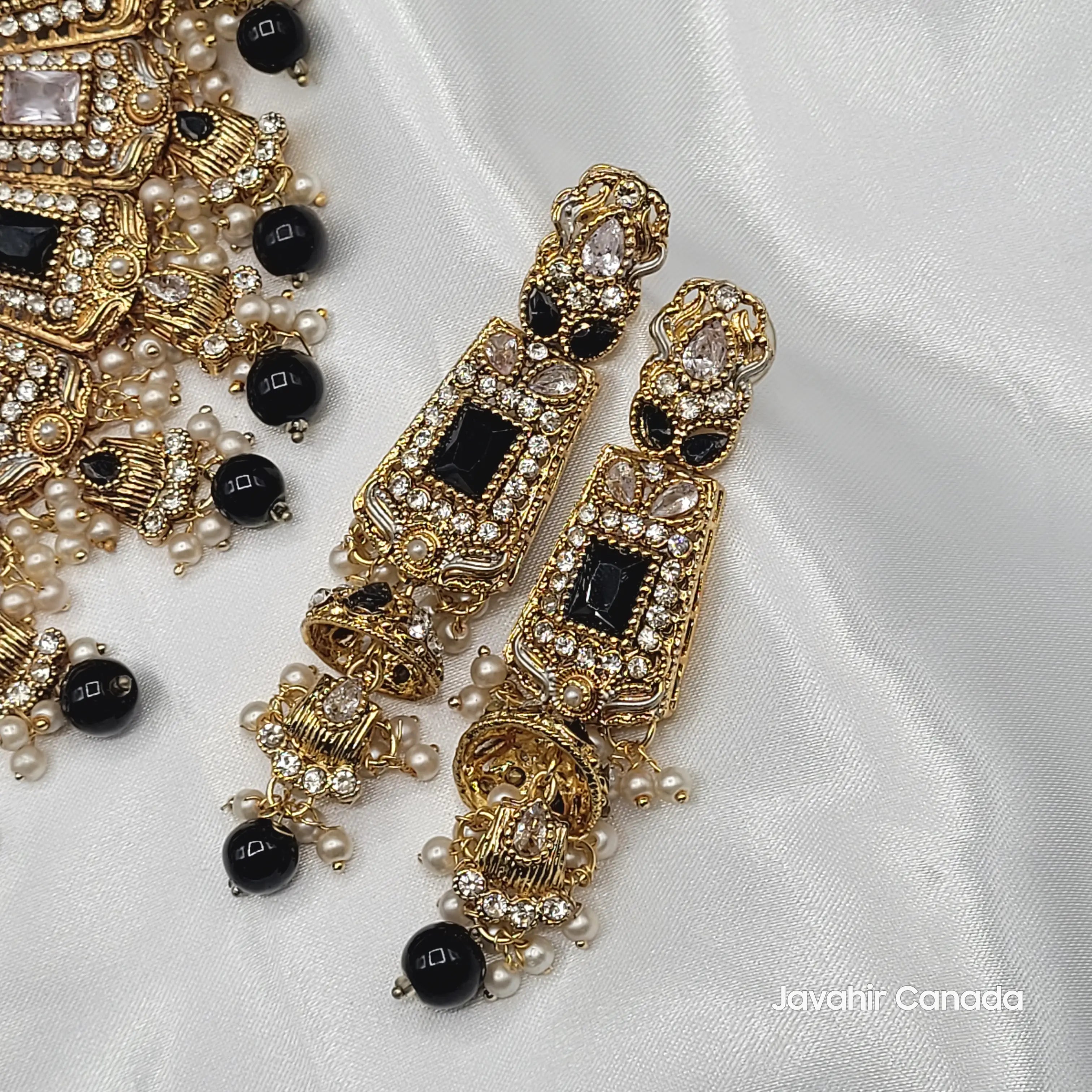 Gold and black earrings on a white fabric background and a "Javahir Canada' watermark