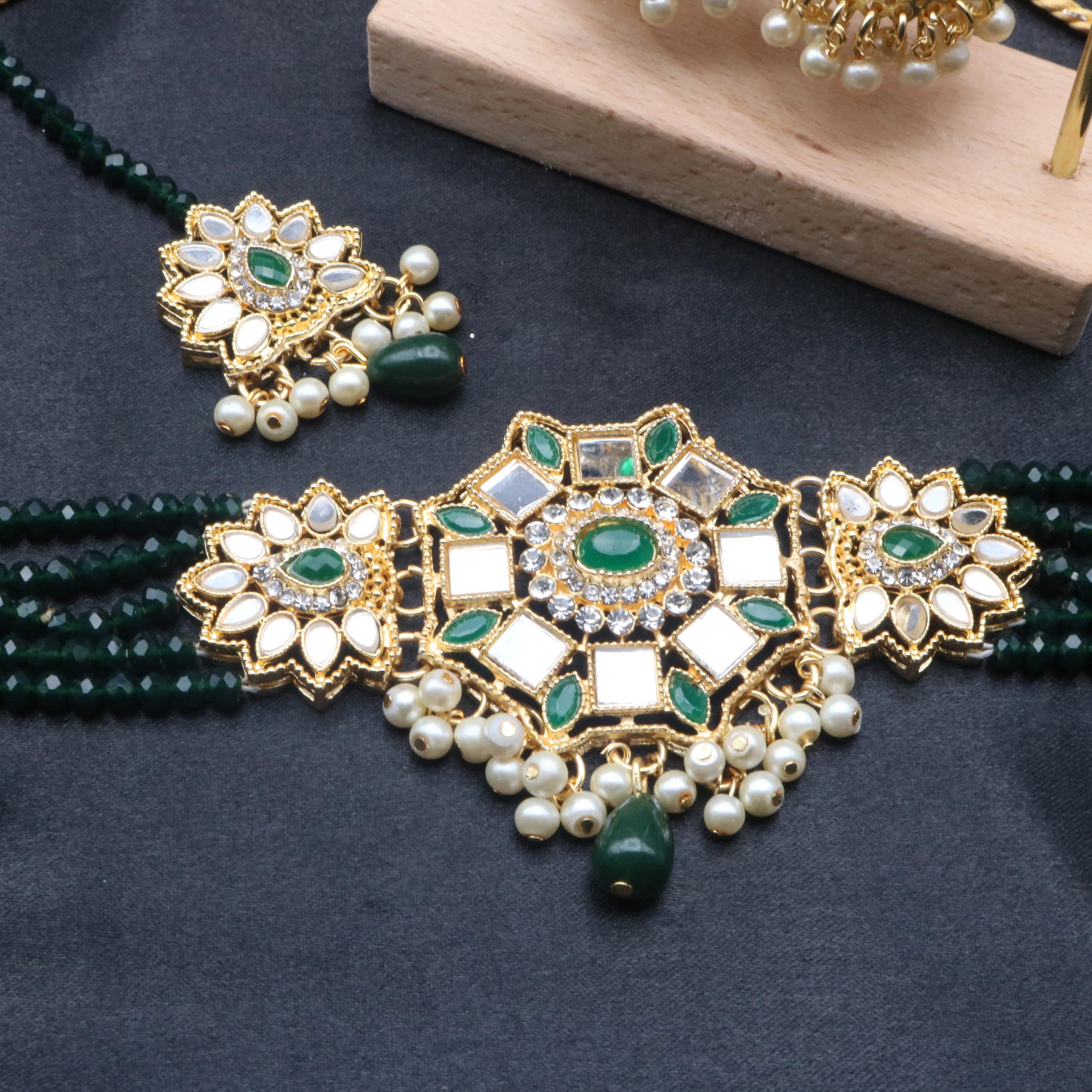 Close-up of Zinnia's central kundan pendant with green stones and pearl dangles
