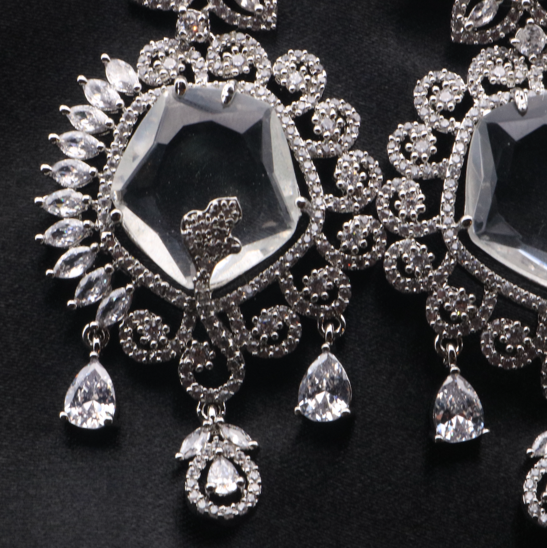 center closer view of pair of silver American diamond earrings with clear gemstones. Stainless steel and waterproof.