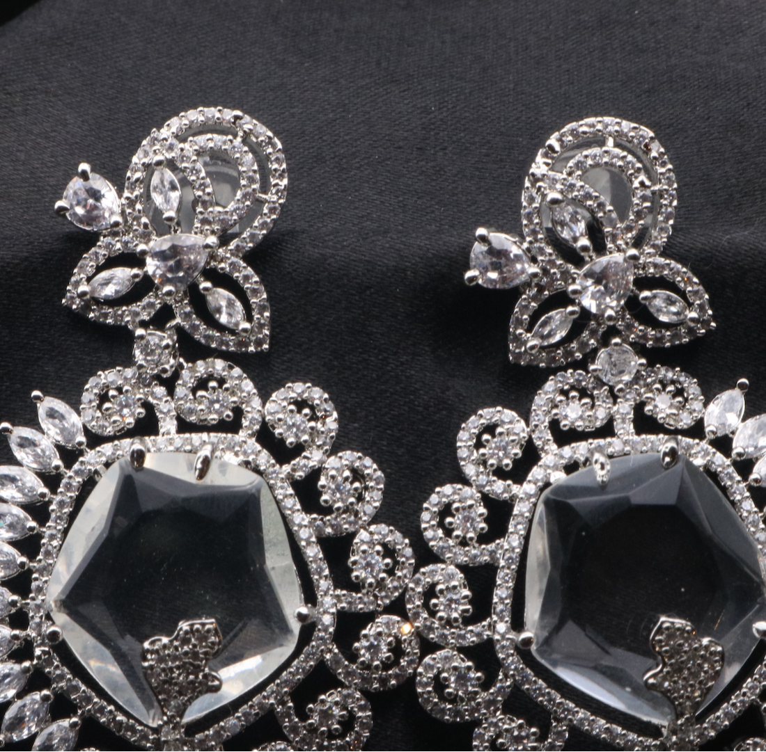 top view of pair of silver American diamond earrings with clear gemstones. Stainless steel and waterproof.