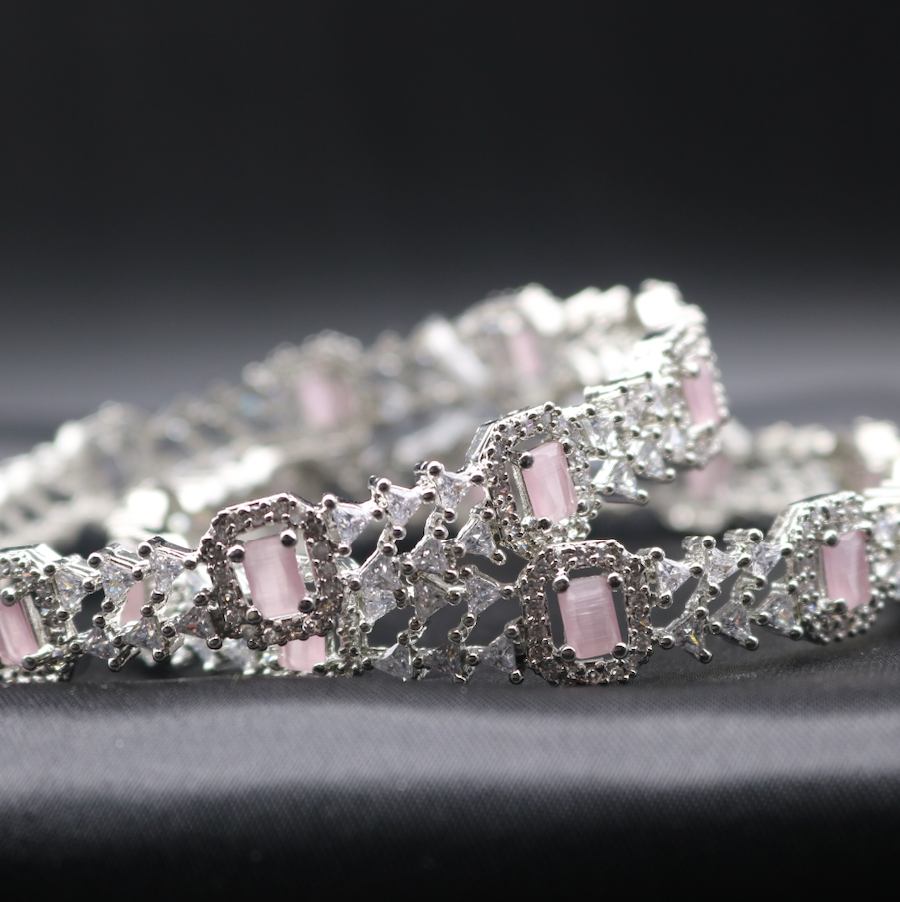 a pair of stainless steel bangles adorned with sparkling American diamonds and pink gemstones