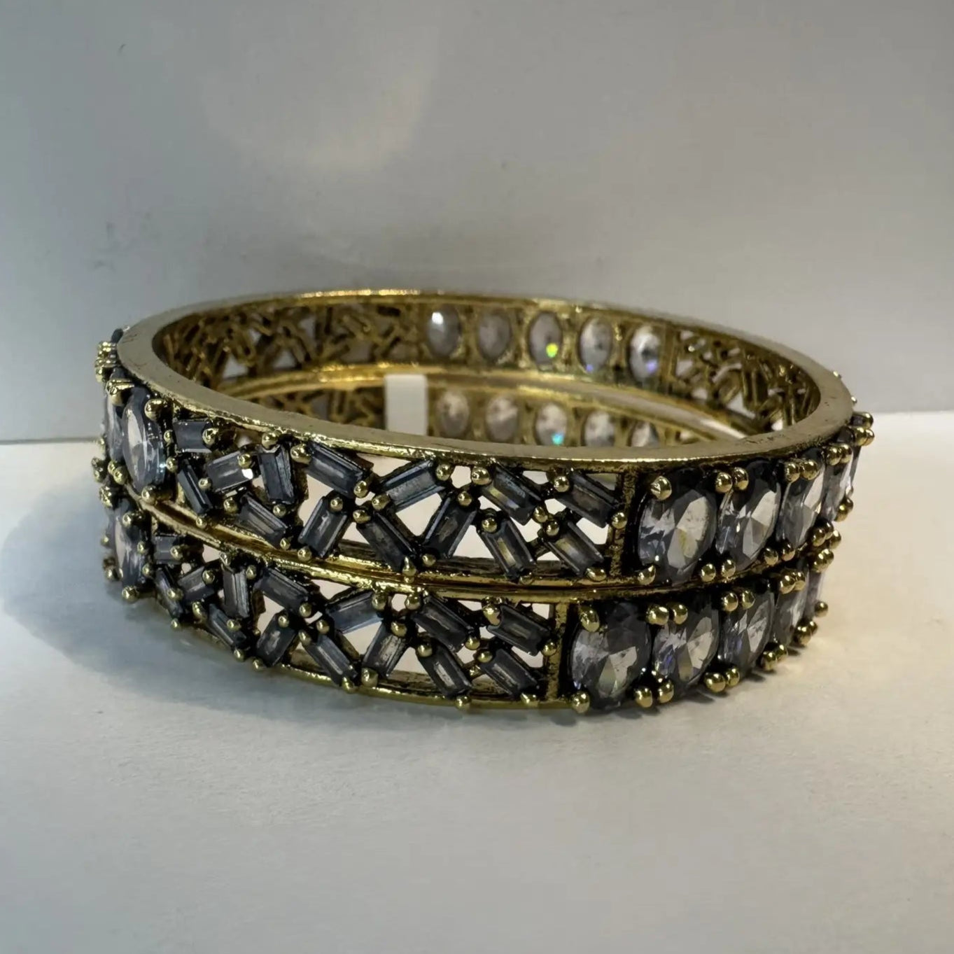 Pair of gold and black beaded bangles on a white surface