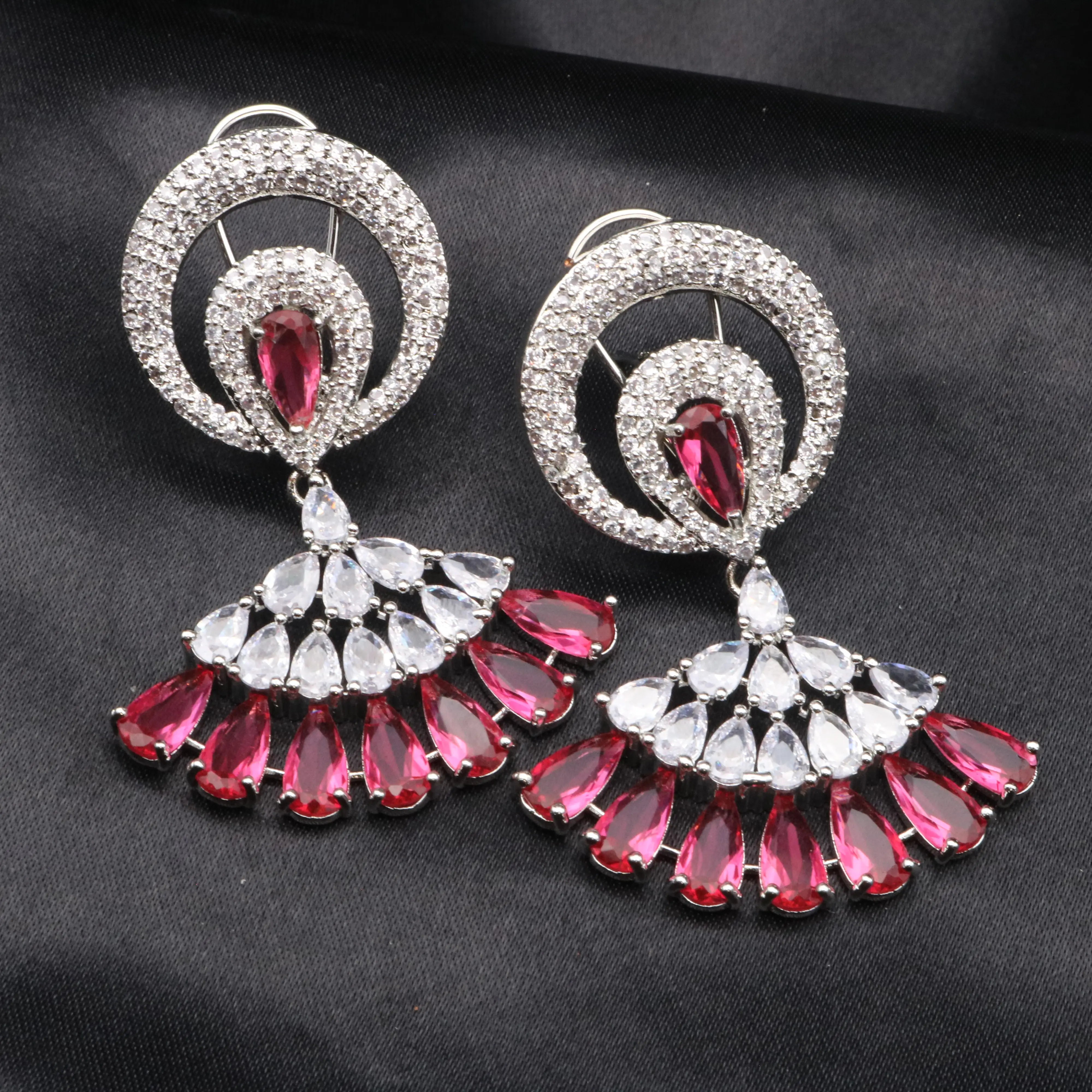 Pair of earrings with pink and clear gemstones on a black background